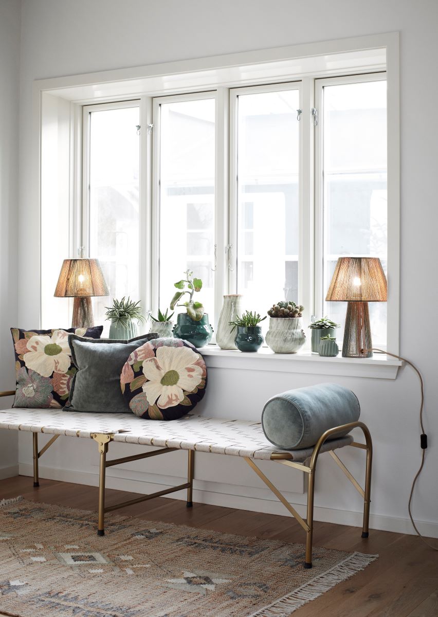 embroidered cushions on a bench in front of a window