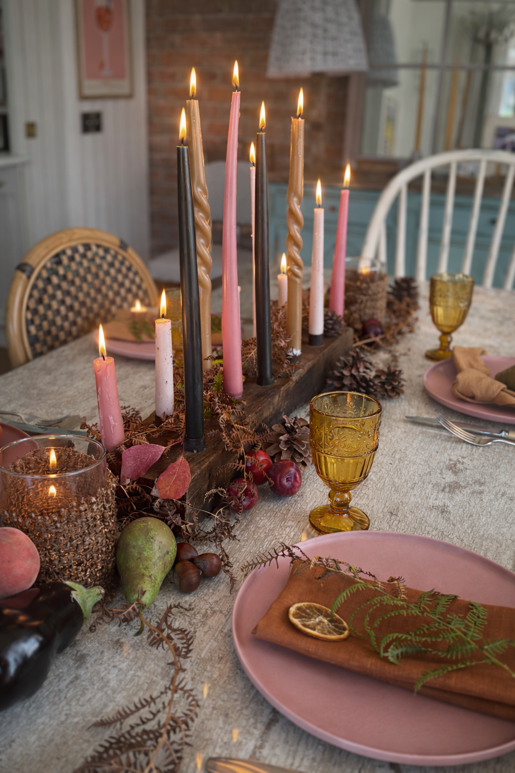 Decorative table setting with candles, plates, and glasses in a cozy indoor setting.