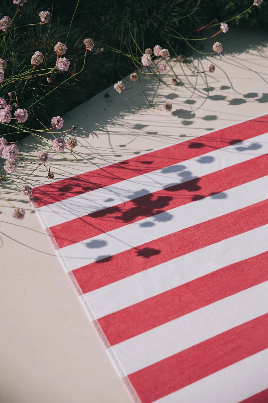 Berry striped retro beach towel laid out on sand
