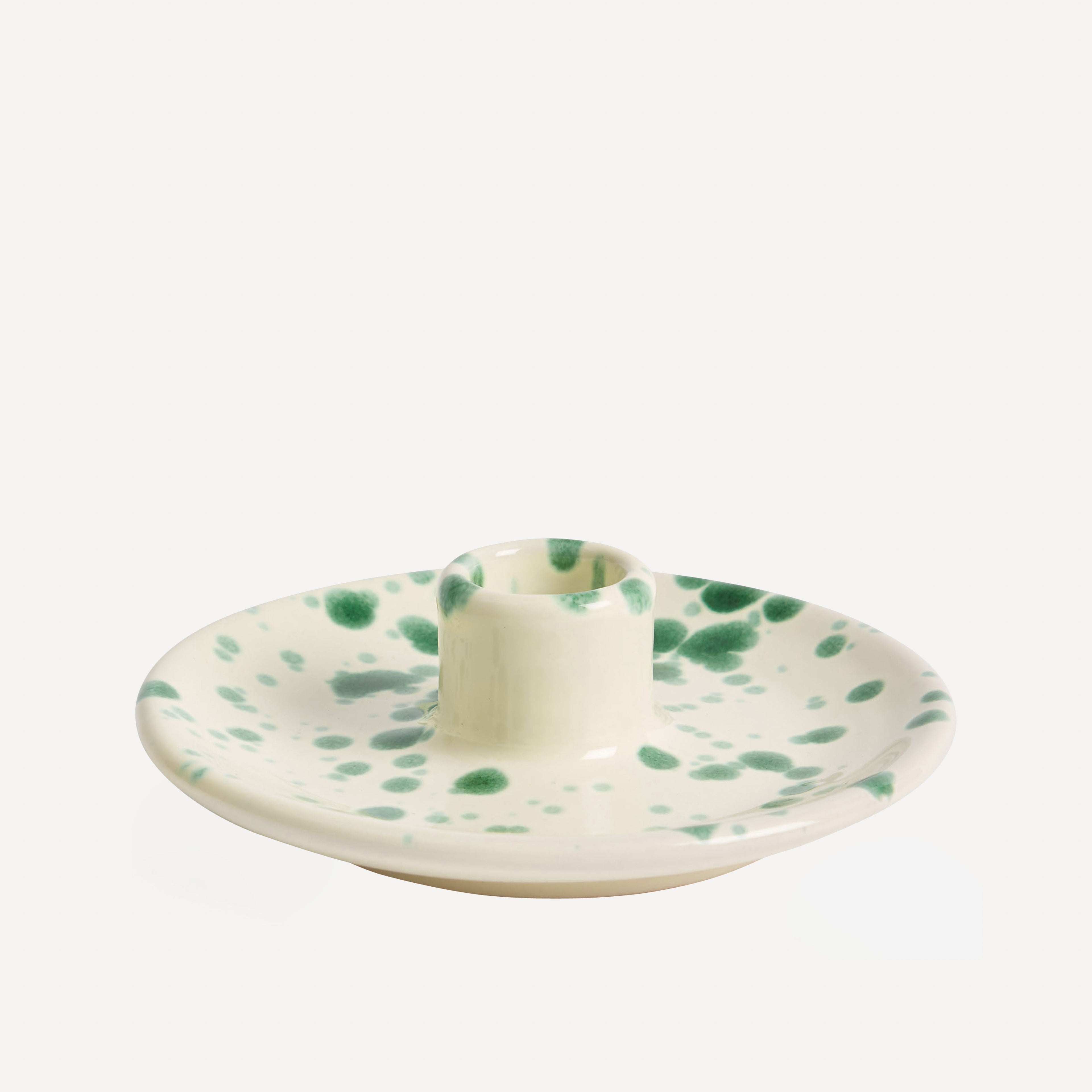 A ceramic splatterware candle holder with a multicolored dot pattern in green and brown tones on a white background.