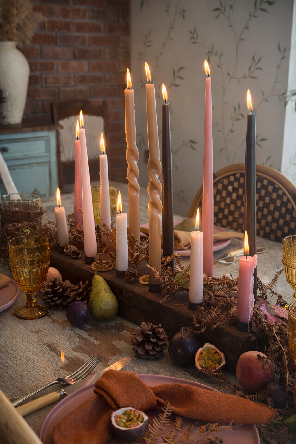 Rustic Autumnal table setting with burning candles , ochre glassware and dusky pink tableware