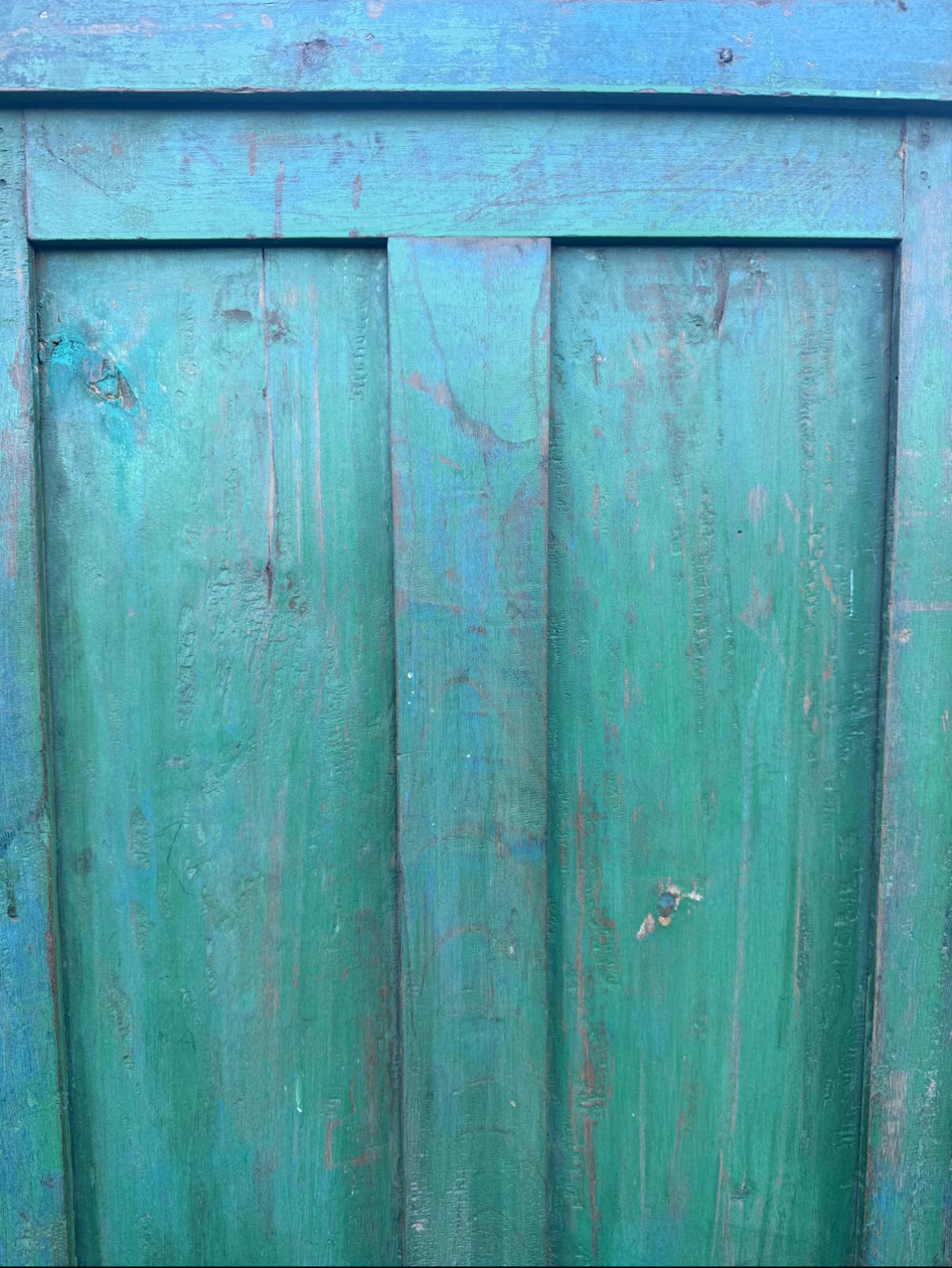 Close-up of a weathered wooden door with peeling green paint