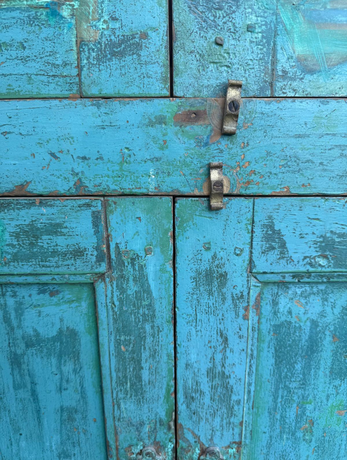 Rustic wooden door with peeling green paint and metal latch.