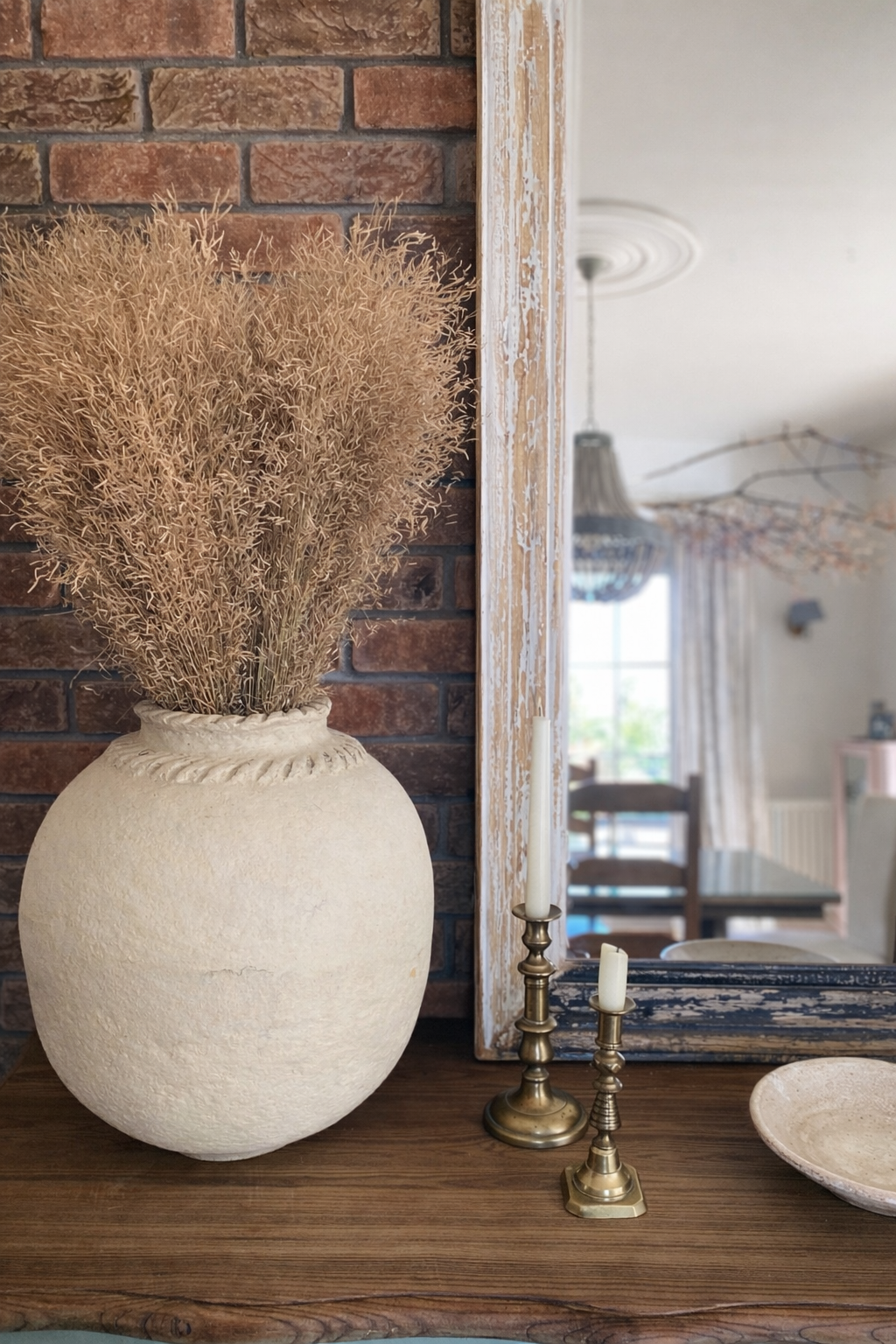 Cream papier-mache vessel on a wooden surface next to a mirror.
