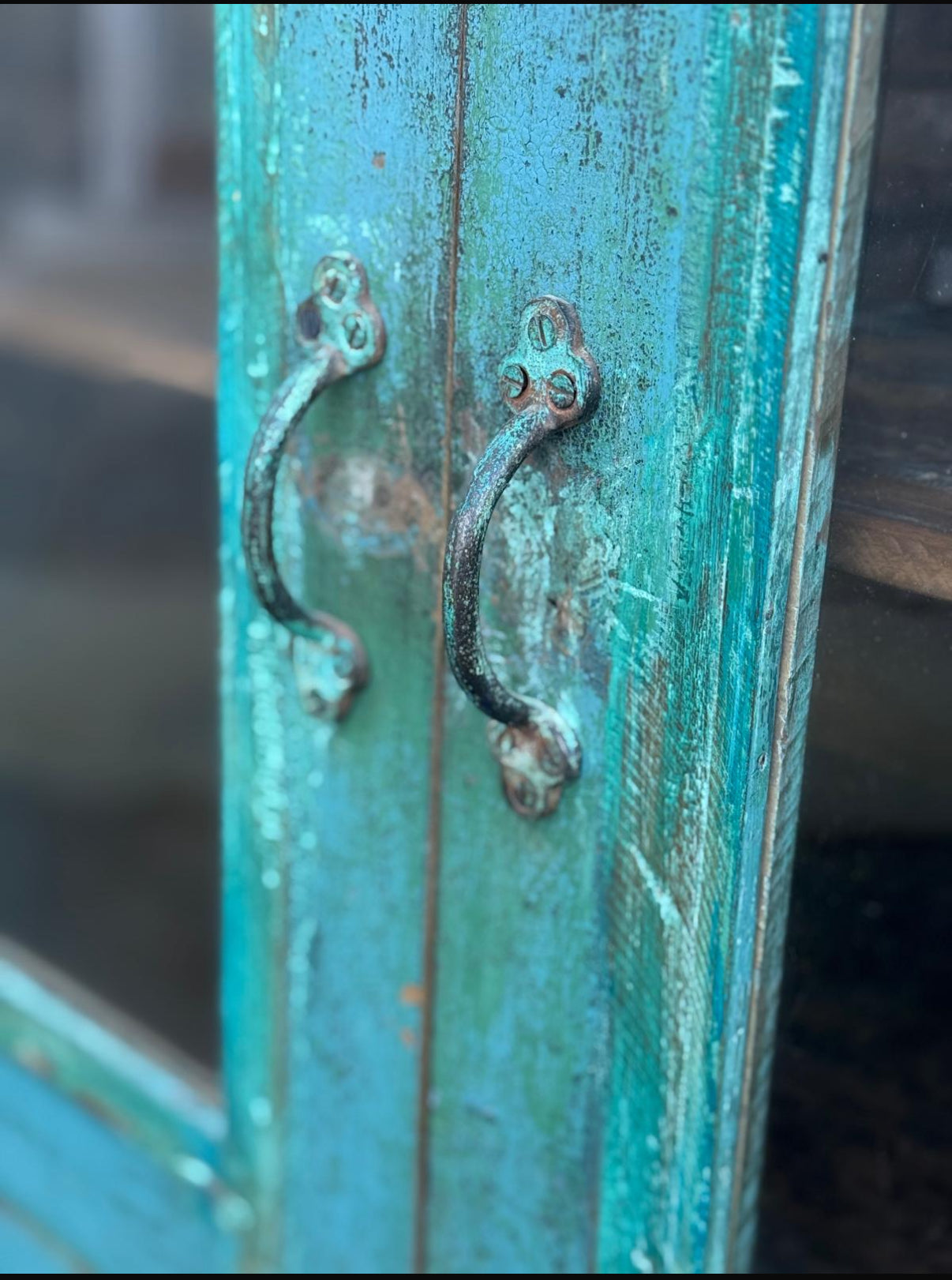 Close-up of a weathered turquoise door with two handles.