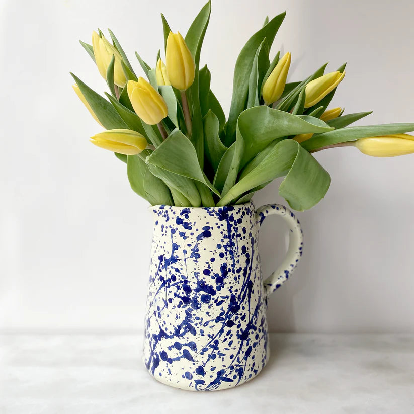Close up of Blue splatter Italian ceramic pitcher with yellow daffodils in white setting
