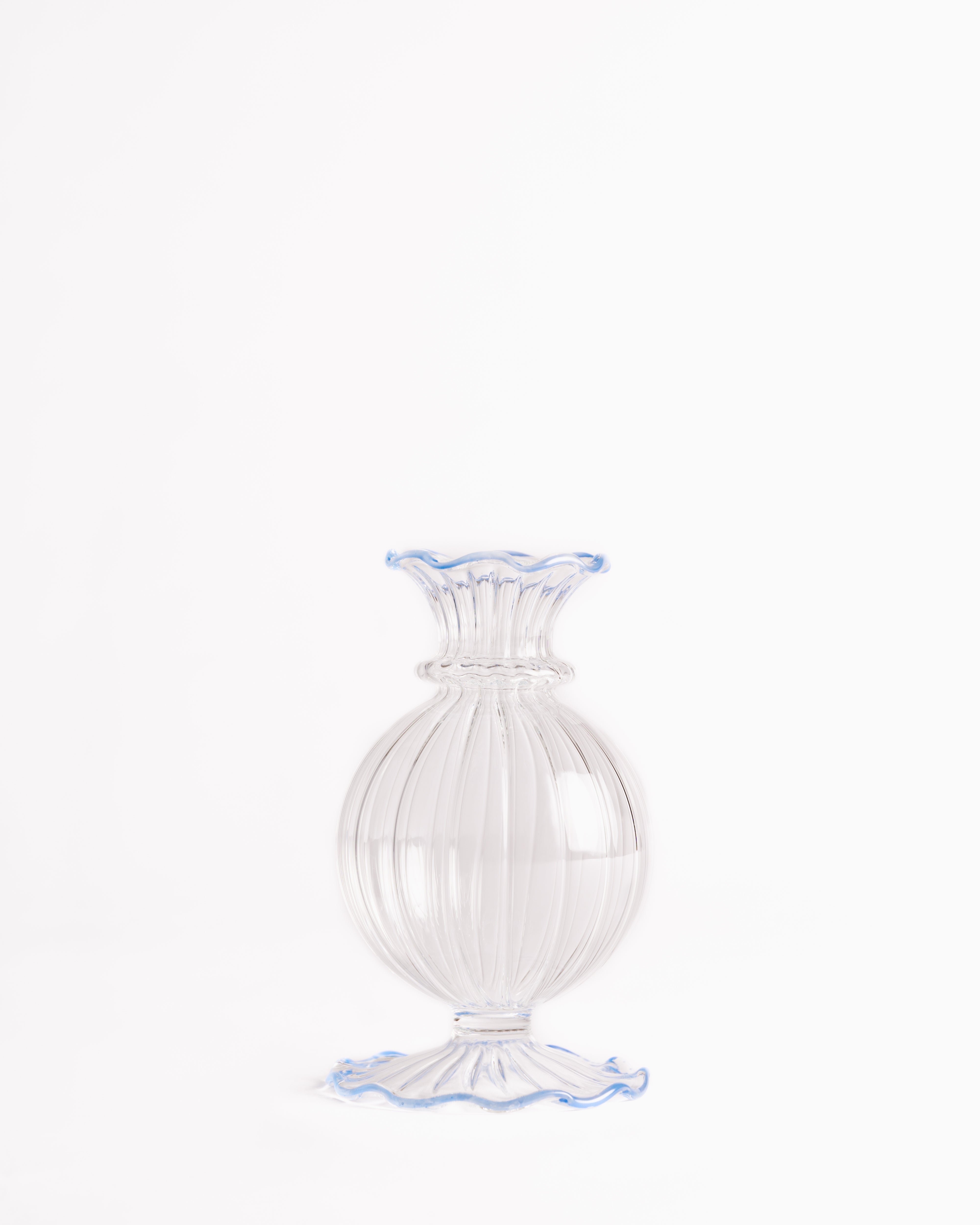 A clear glass bud vase with a frilly edge design, featuring a swirling pattern and a blue rim at the top.
