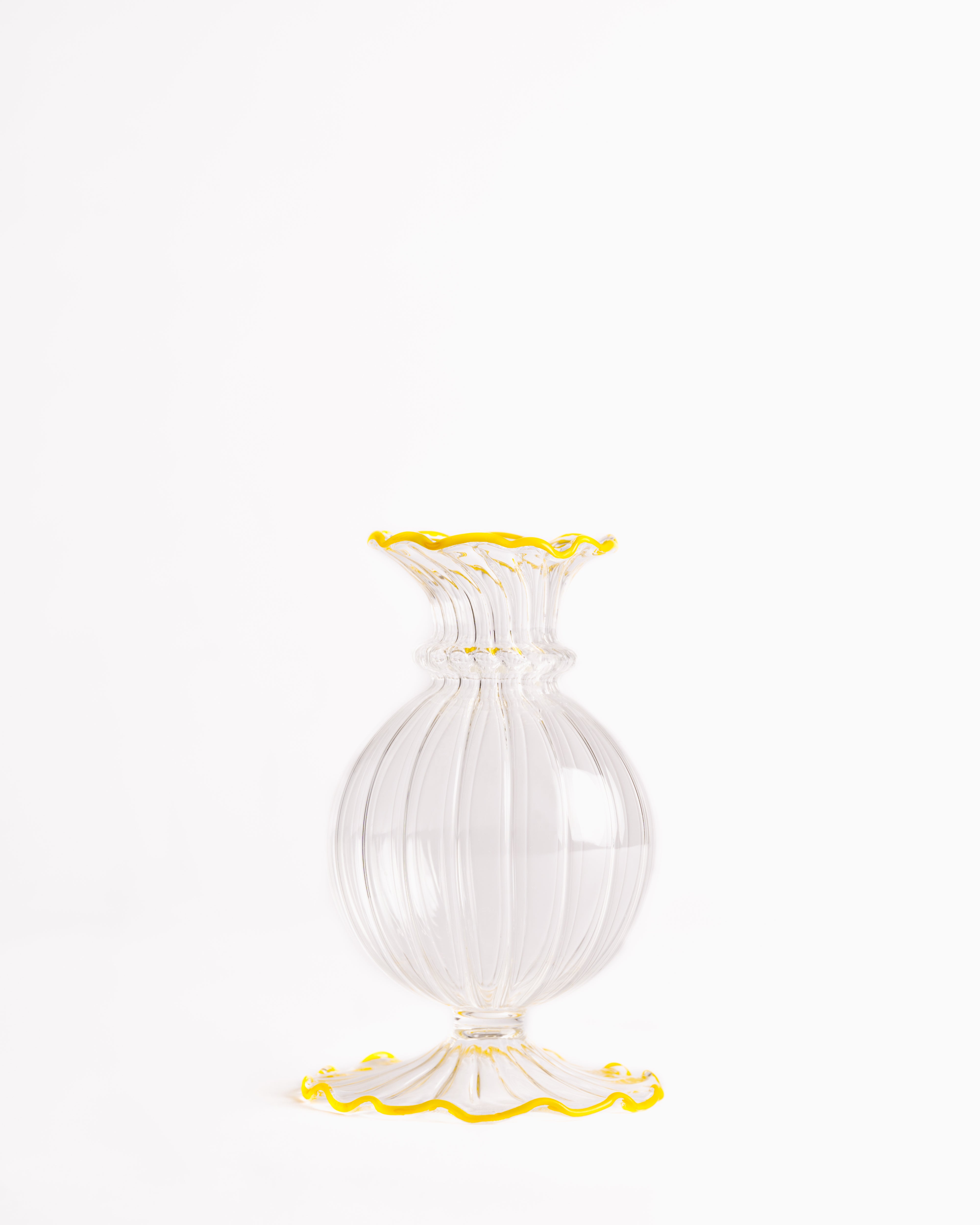 A clear glass bud vase with a frilly edge design, featuring a swirling pattern and a blue rim at the top.