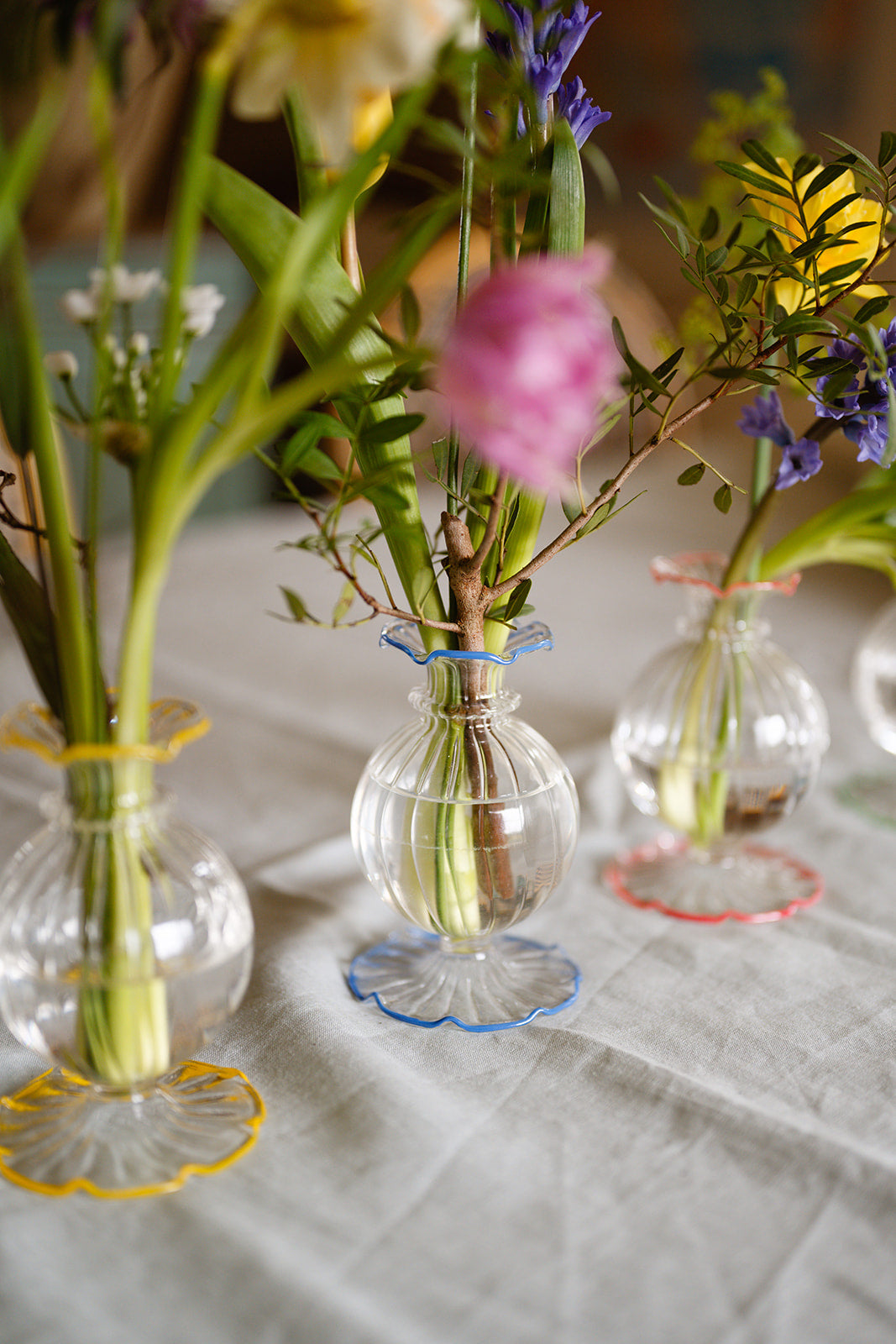 Small glass vases with floral arrangements on a tablecloth