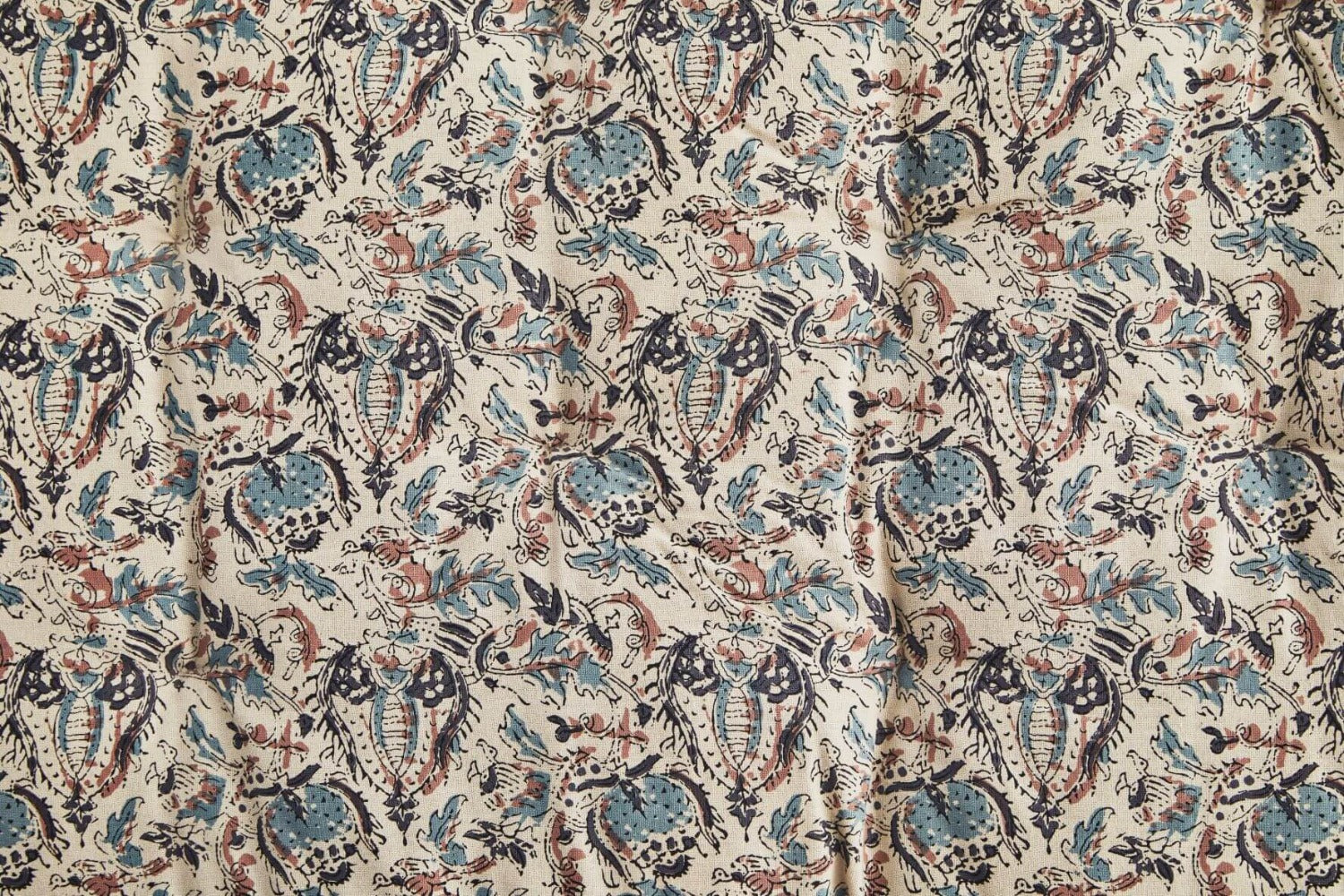 Close up detail of block print floral mattress in aqua, beige, black, dusty rose tones