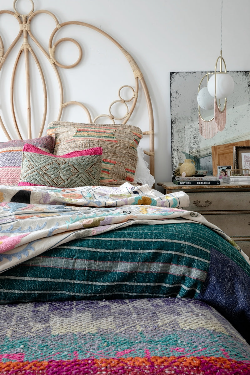 Bedroom with colorful bedding and decorative pillows on a bed with a decorative headboard.