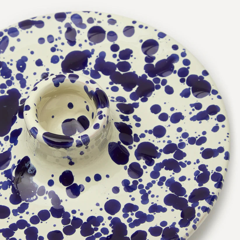 A ceramic candle holder with a blue and white splattered pattern