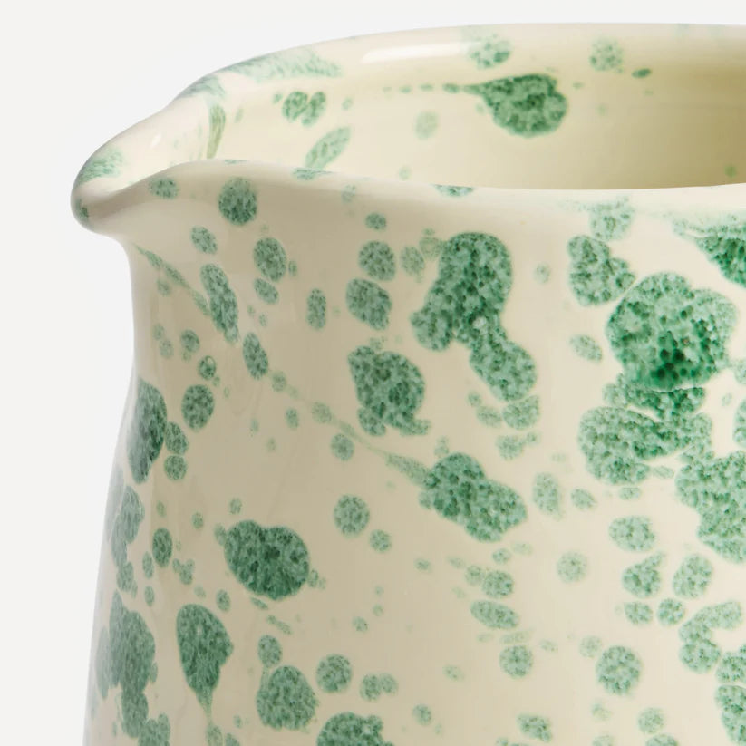 A ceramic splatter jug with a green and white color scheme and a textured 'splatter' pattern.