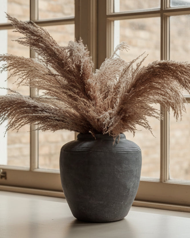 Grey cement vessel with pampas against windows