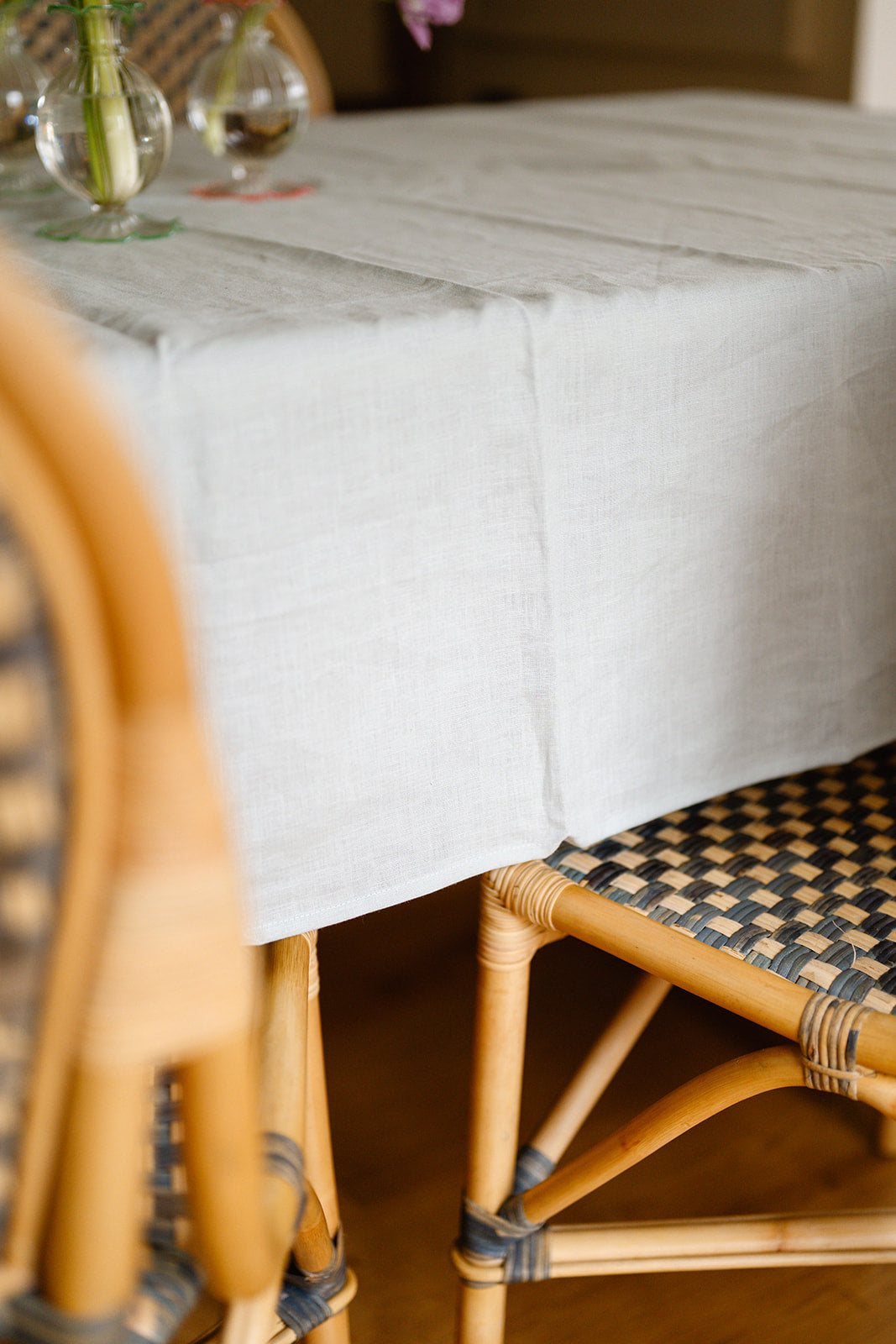 close up shot of duck egg blue tablecloth draped over table next to woven bistro chairs