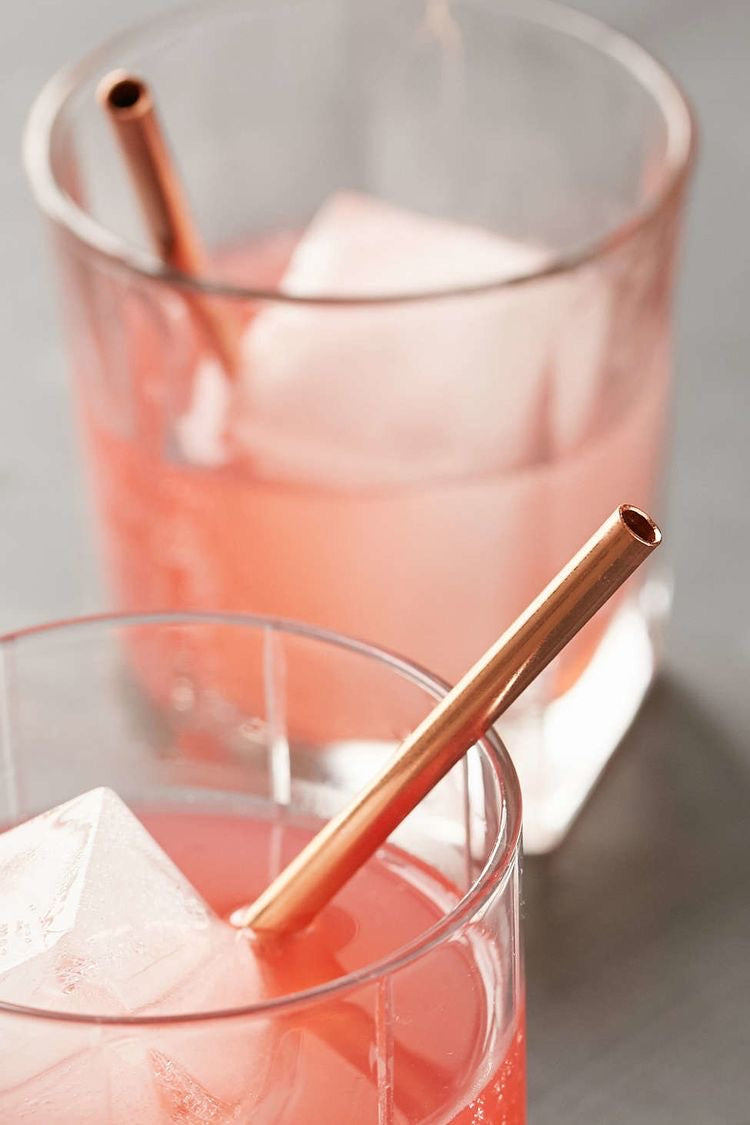 close up of gold metal straws in pink coloured cocktail