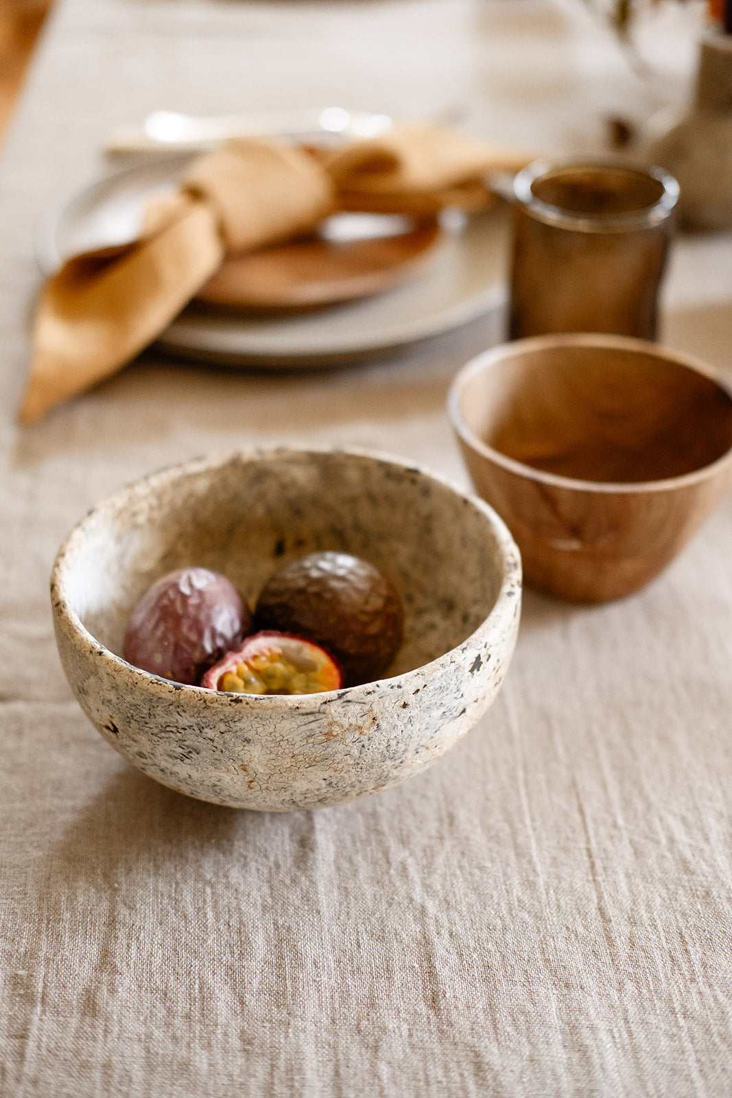 This image elegantly displays a natural linen tablecloth with fringes, laid out on a dining table. The tablecloth, crafted from 100% stonewashed linen, boasts a soft, rumpled texture that adds a touch of casual sophistication to the setting.
