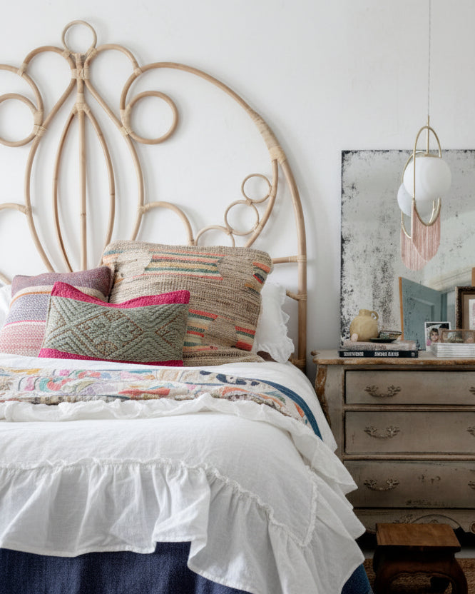 Bedroom with colorful bedding and a rattan scrolled headboard.