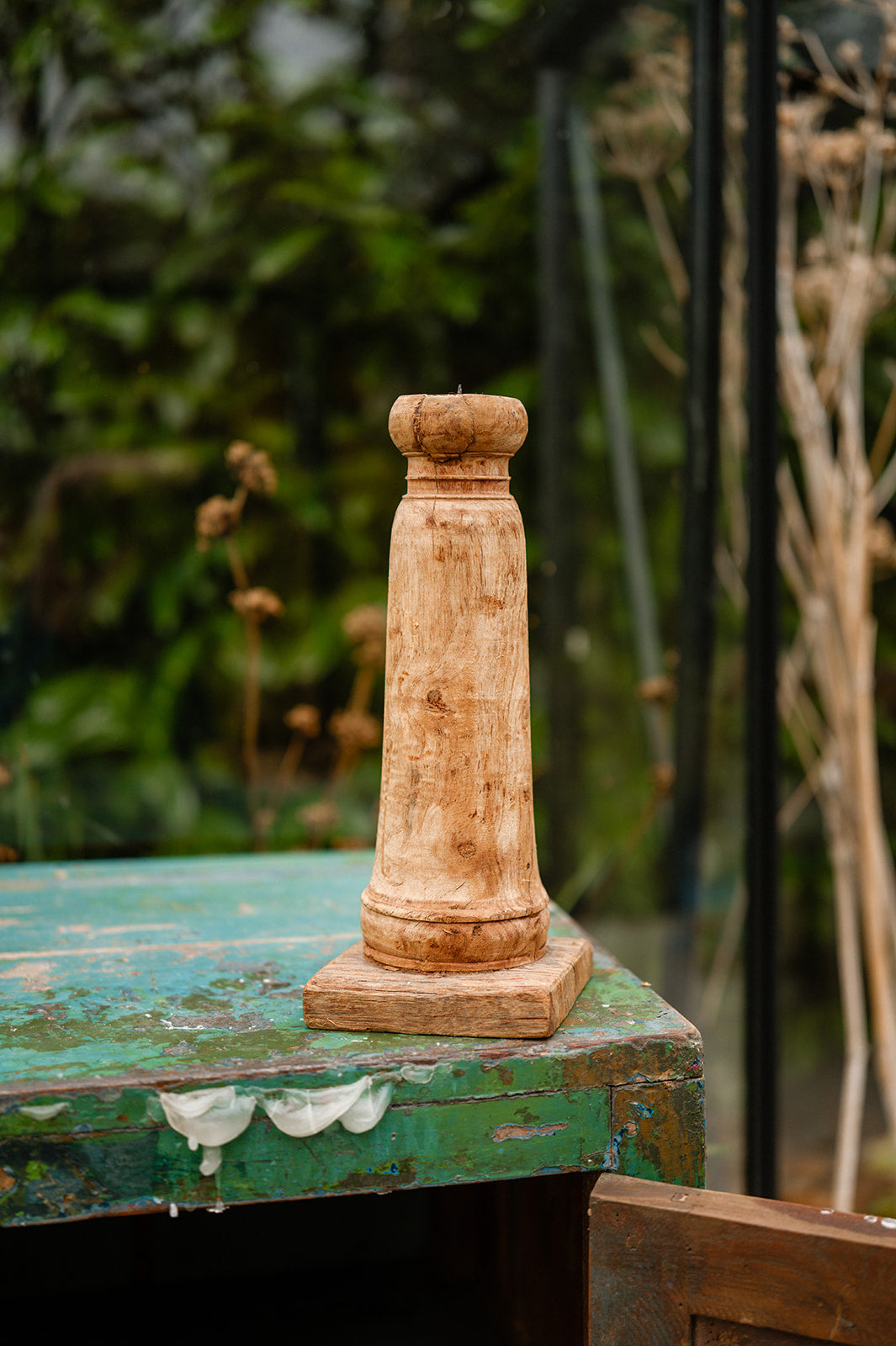 Wooden column on a rustic green surface with blurred natural background