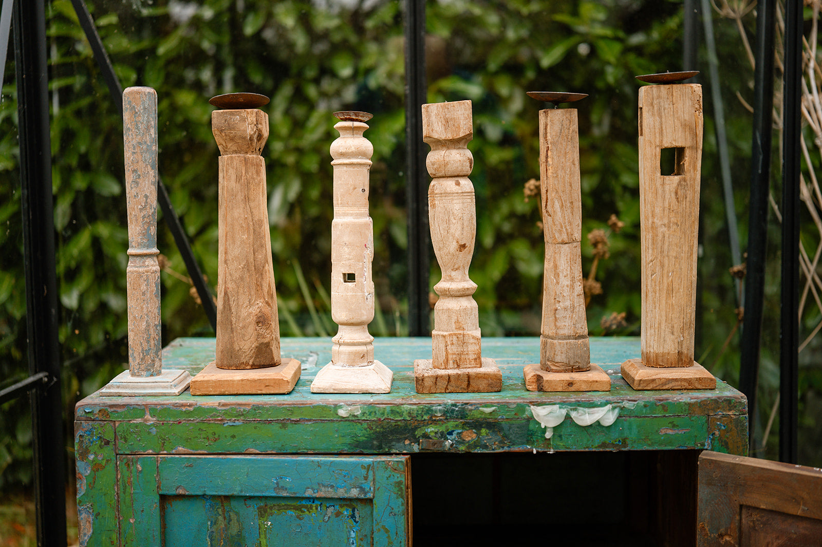 Set of wooden candlesticks on a rustic green cabinet with a blurred natural background