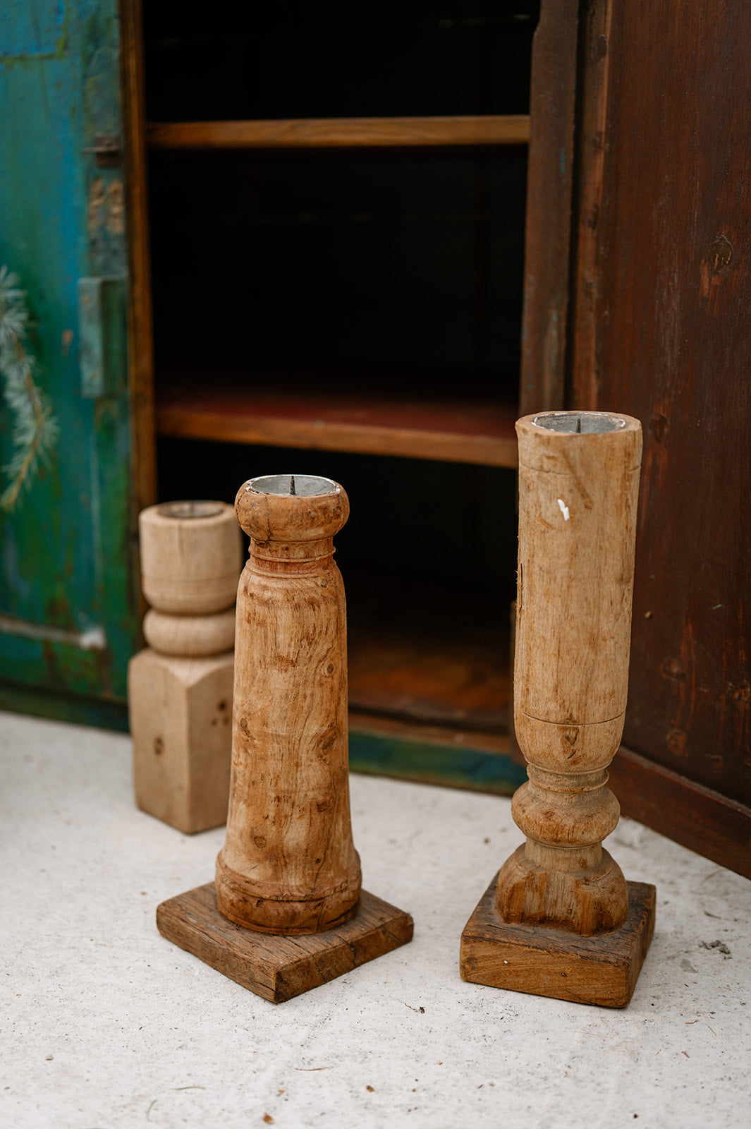 Two wooden candle holders on a textured surface with a rustic background.