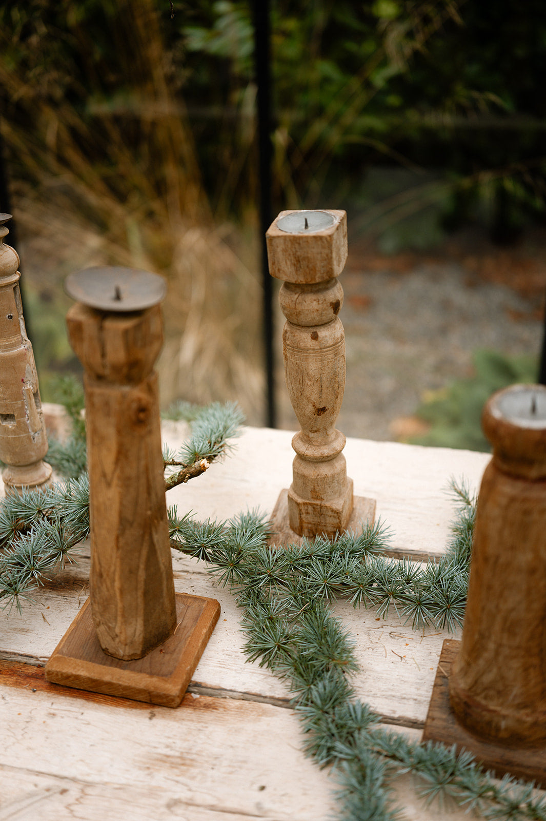 Wooden candle holders on a rustic wooden surface with greenery