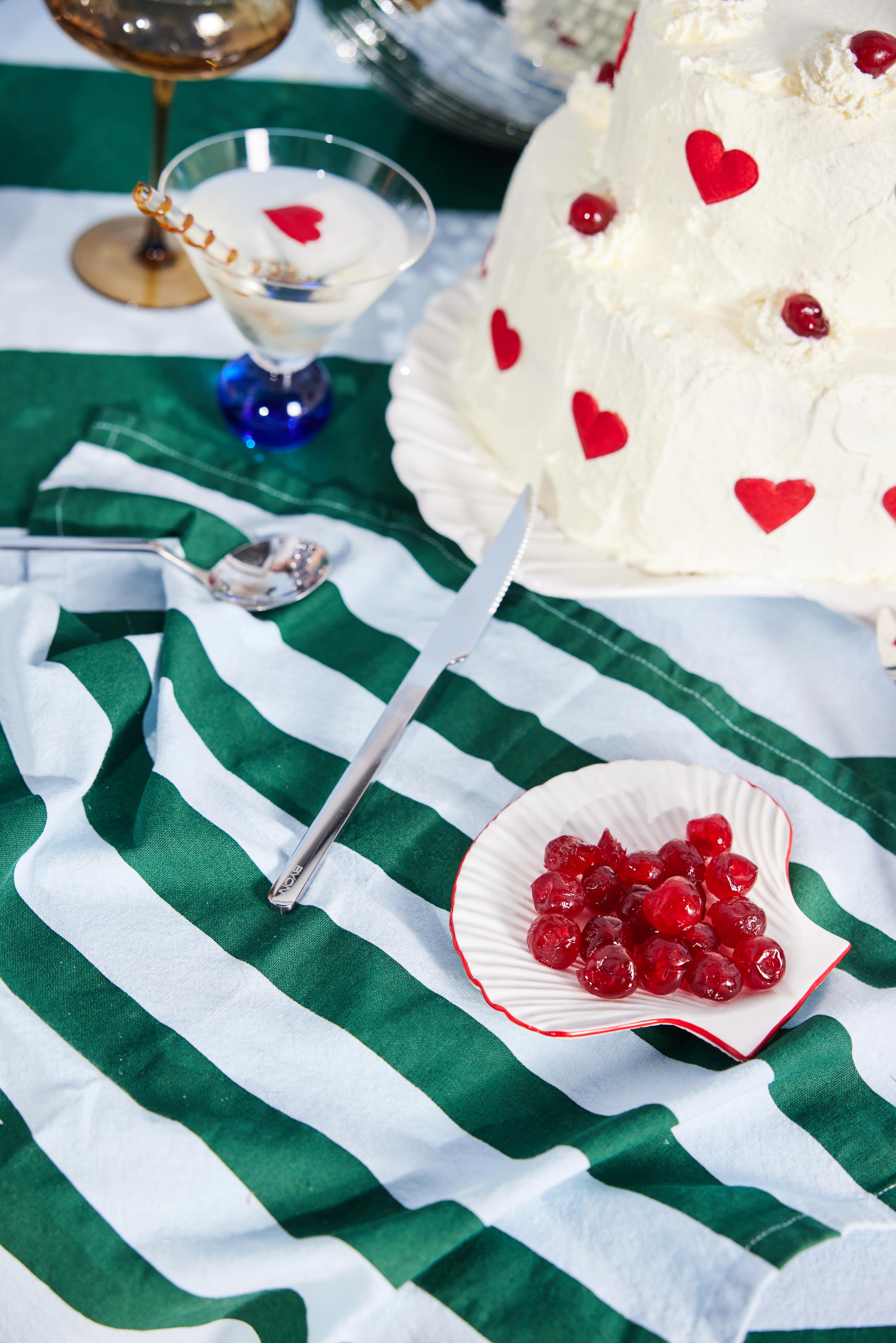 white shell plate with red outline with berries on green and blue striped tablecloth