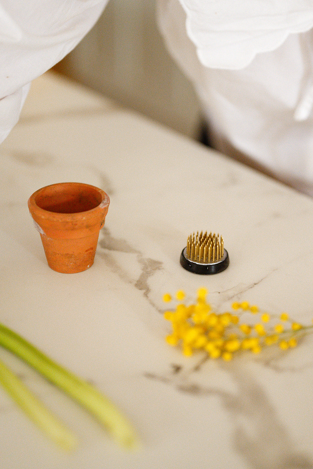 Small flower frog on white counter next to mini vintage terracotta pot