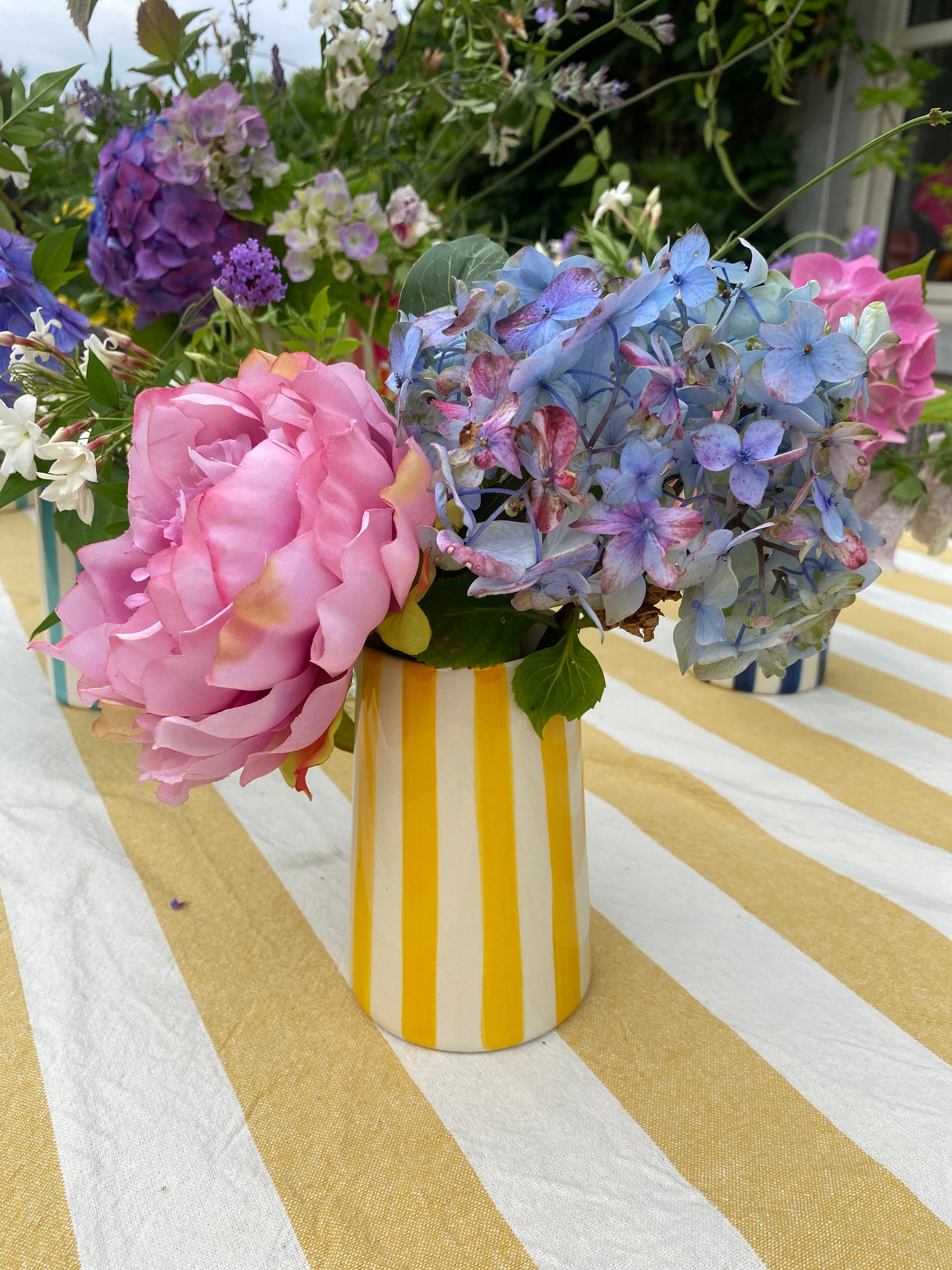 Yellow and white striped handmade ceramic jug on outdoor table