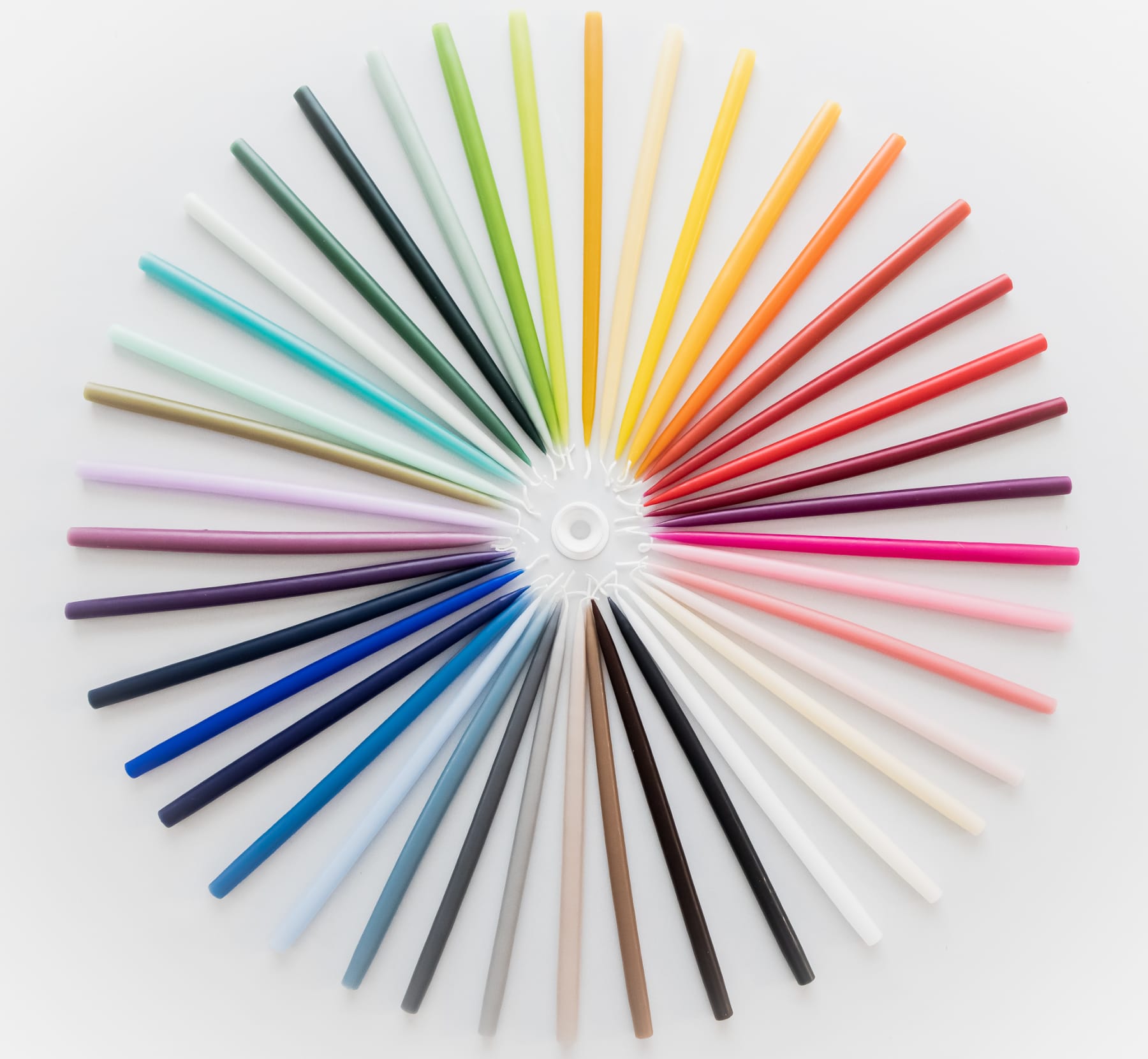 Image of collection of coloured candles arranged in a circle on a white background
