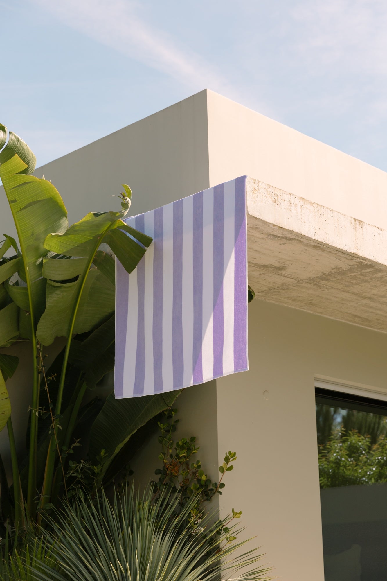 Lavender striped retro velour beach towel draped over balcony among palm trees