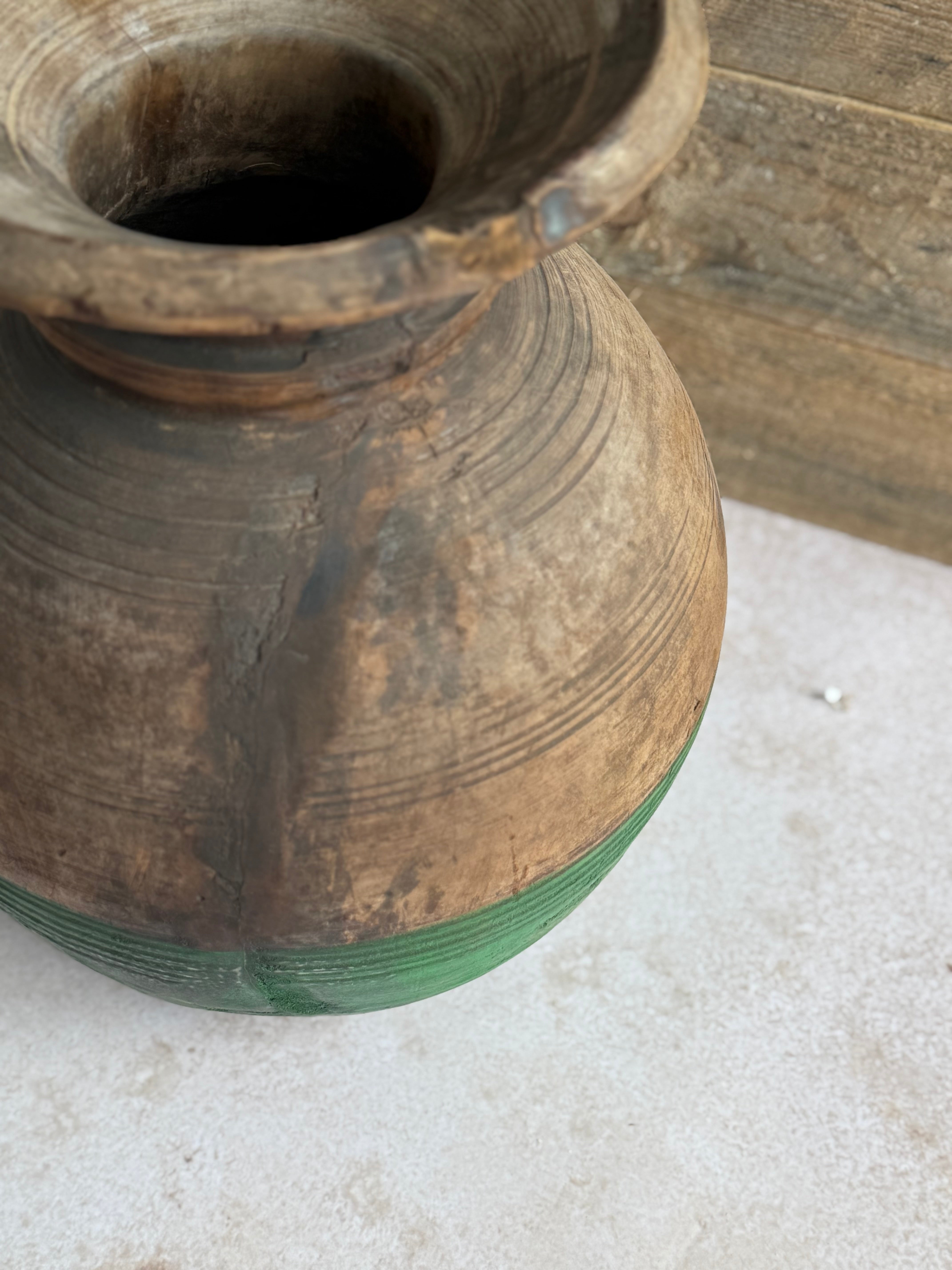 Vintage wooden pot with green base on a light surface.