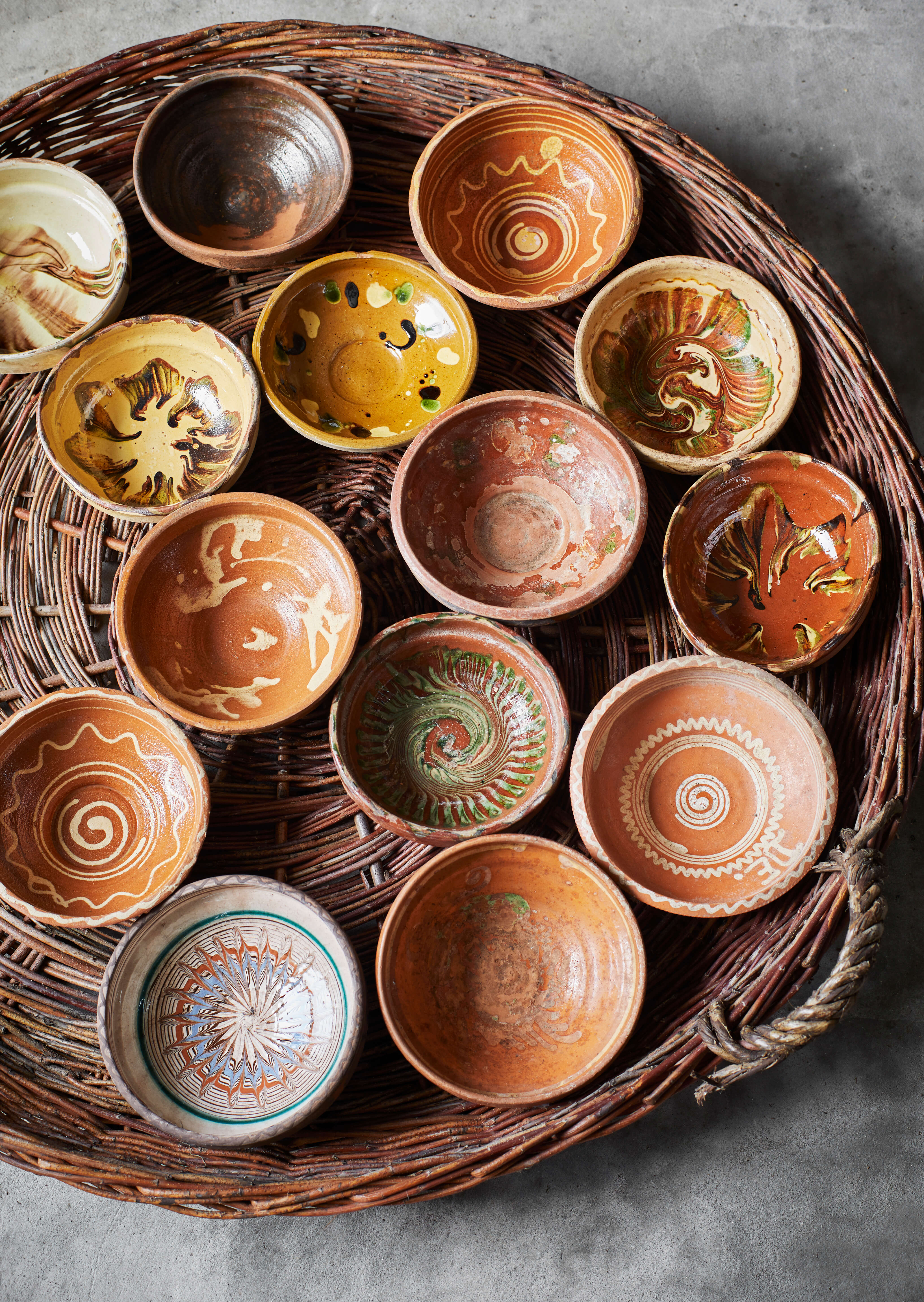 Aerial view of vintage patterned bowls on a wicker handled tray