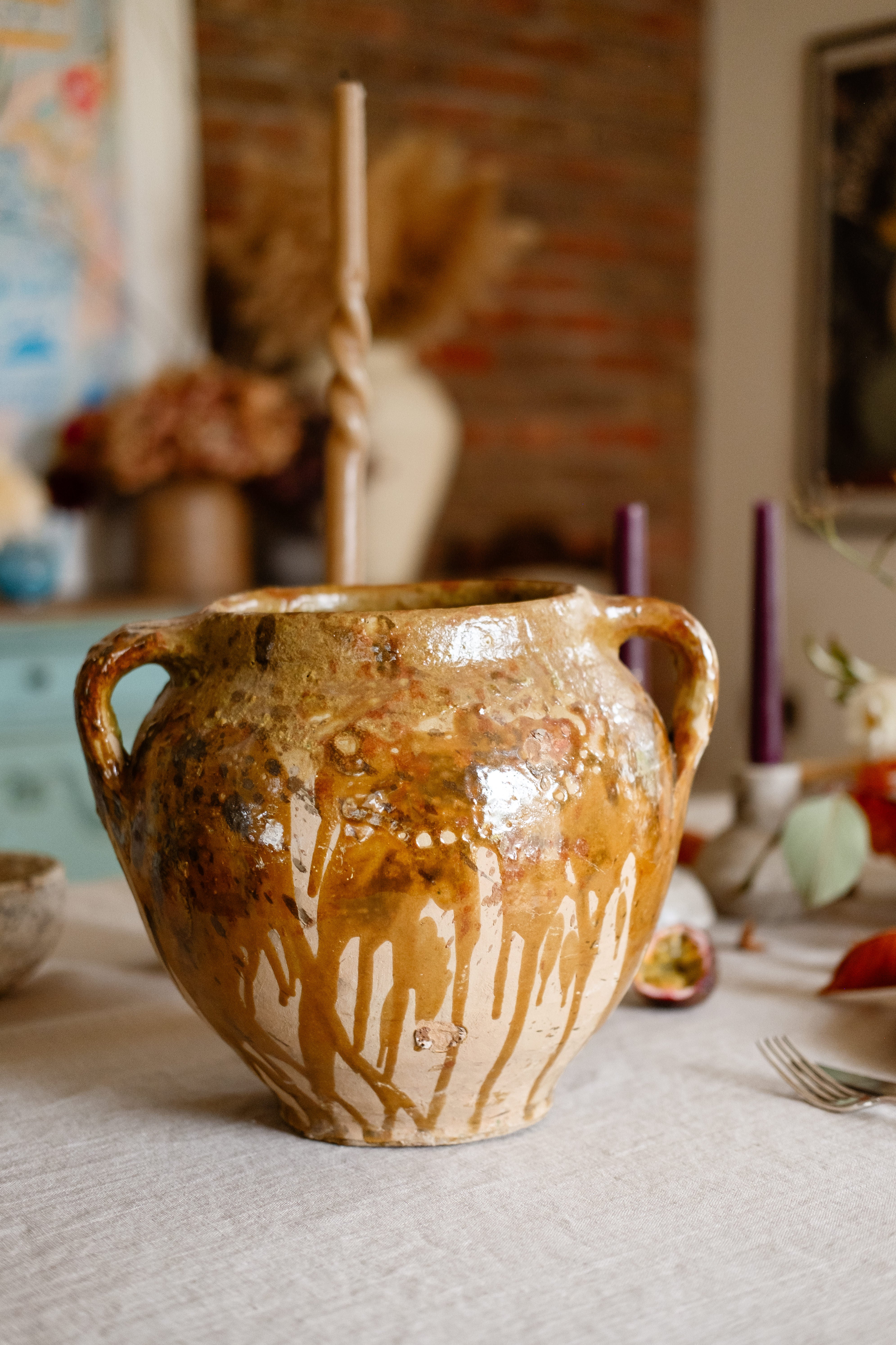 Vintage stoneware vessel with brown and clay tones in a dining room with old brick wall