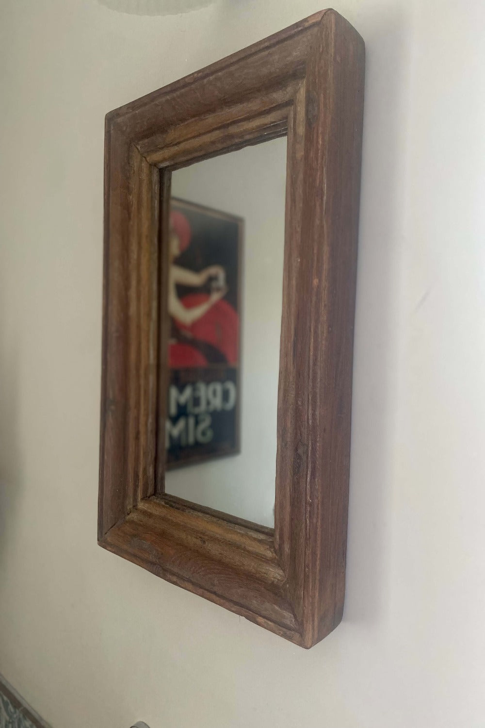 A reclaimed wood mirror with a brown frame, mounted on a wall.