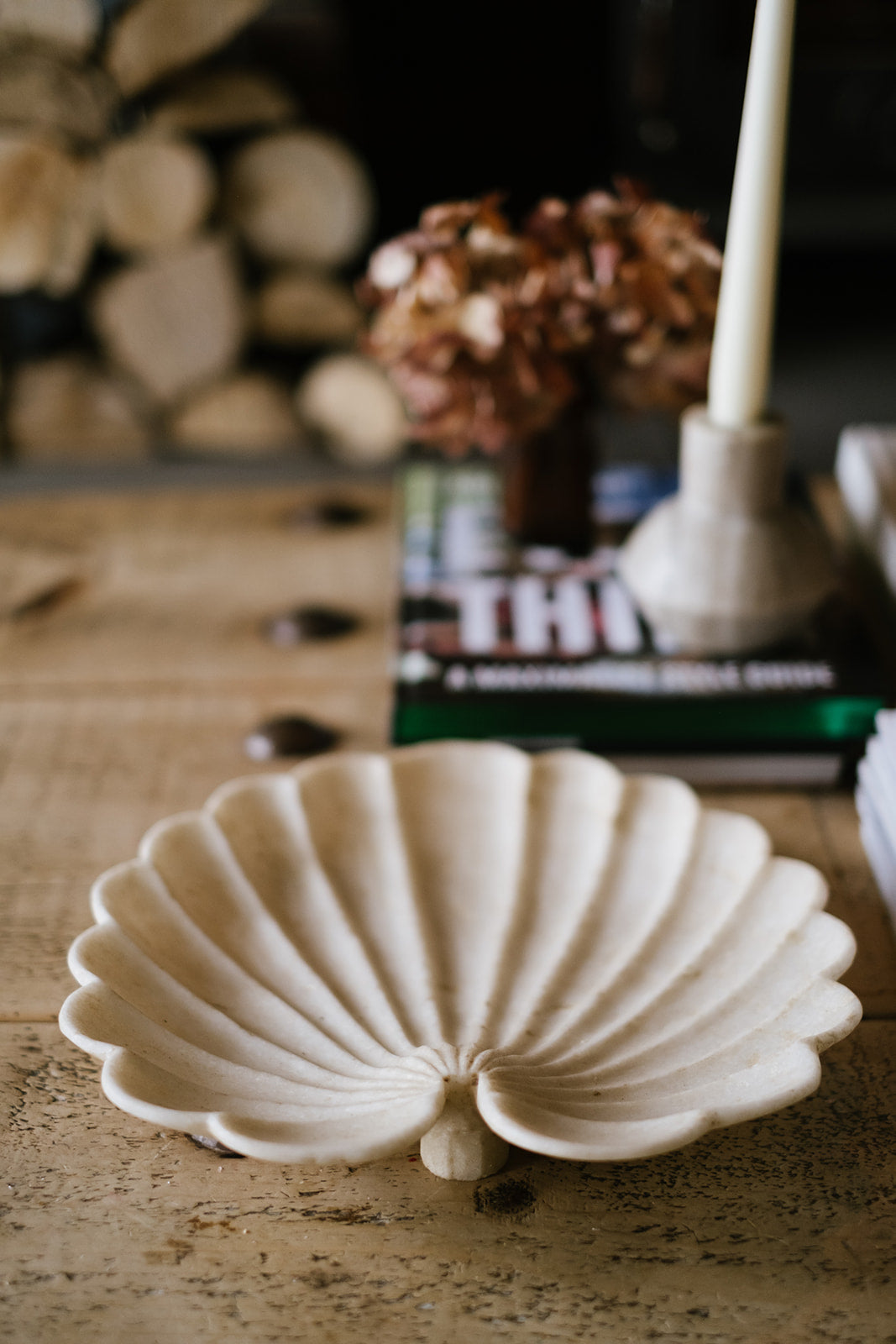 Marble shell plate on wood coffee table with fire logs and candles in background