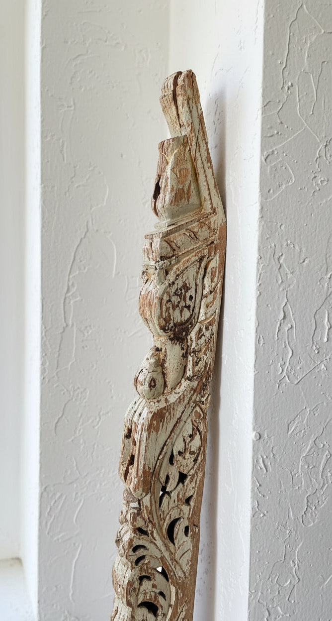 Detail shot of old indian carved panel leaned against textured white wall