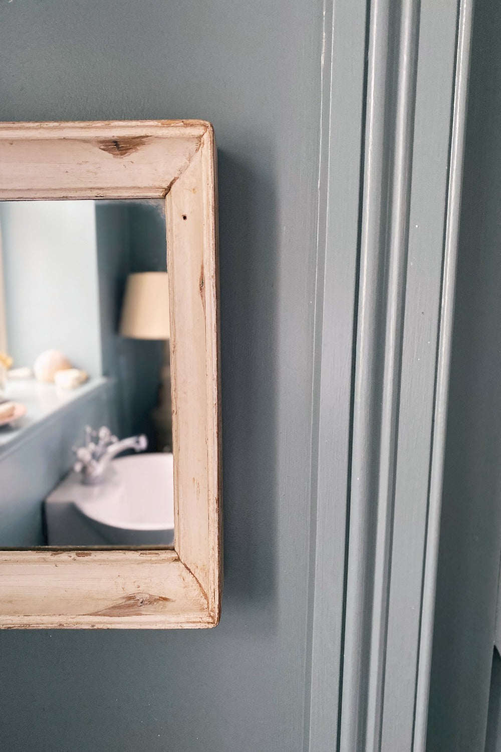 A square reclaimed wood mirror with a natural off-white color, mounted on a wall.