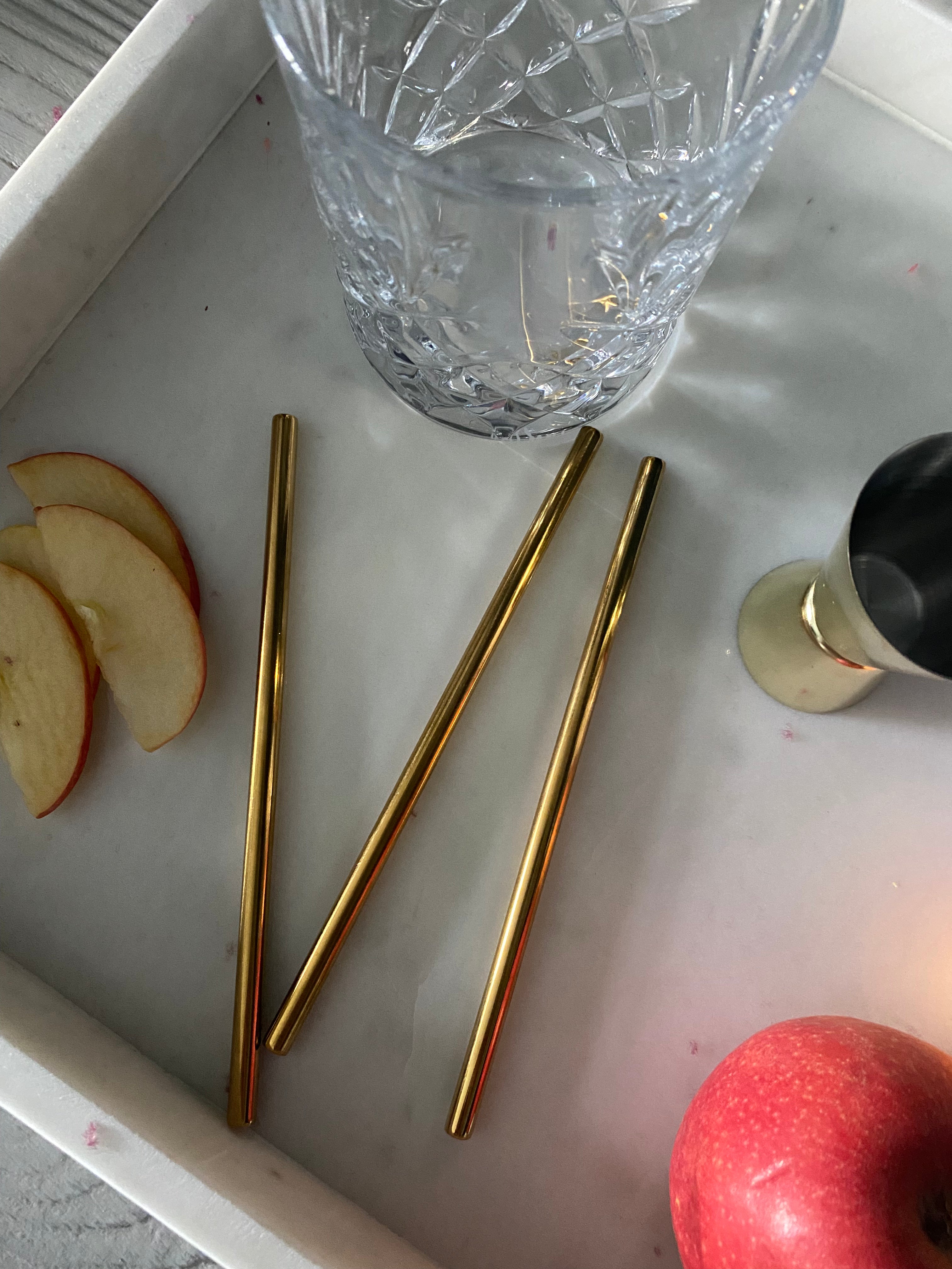 gold metal straws on white marble tray