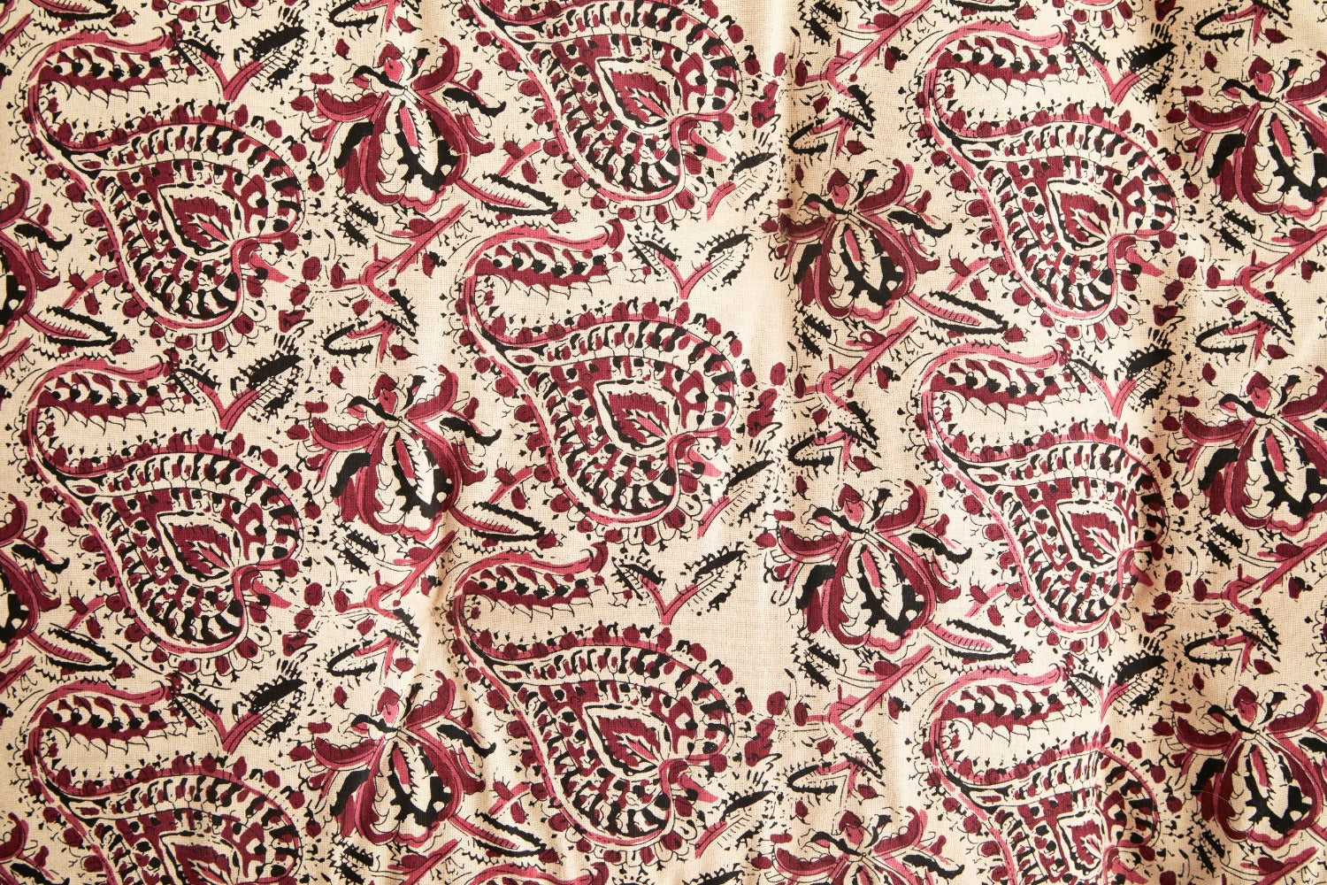Close up detail of block print floral design with raspberry, beige and black tones