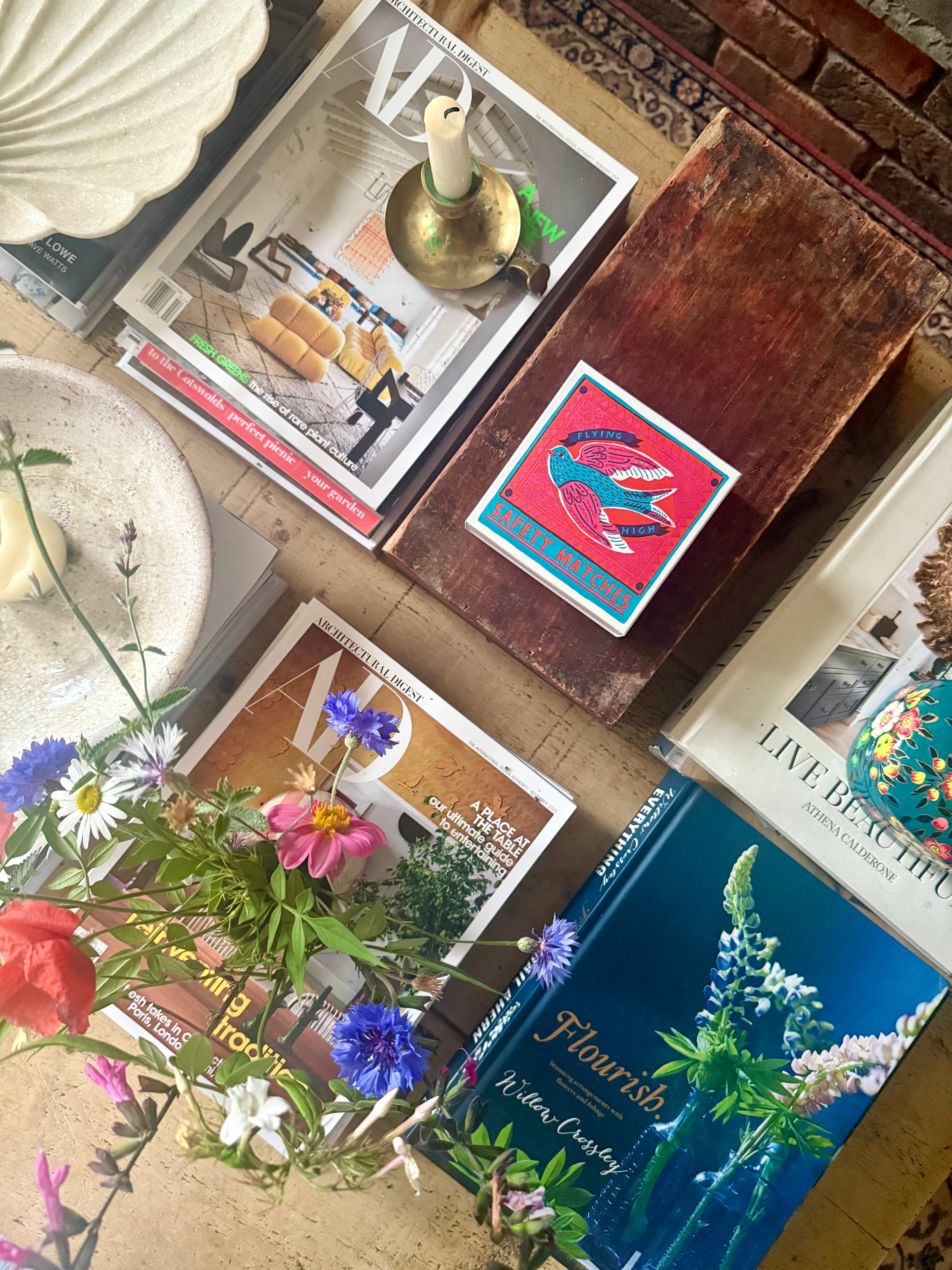 Colourful Coffee table styling with magazines, wild flowers, design matchbox