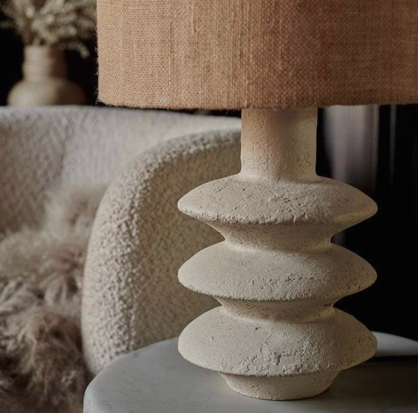 Close up detail shot of Akito lamp with textured ecomix creamy coloured base with jute lamp shade with cream chair in background