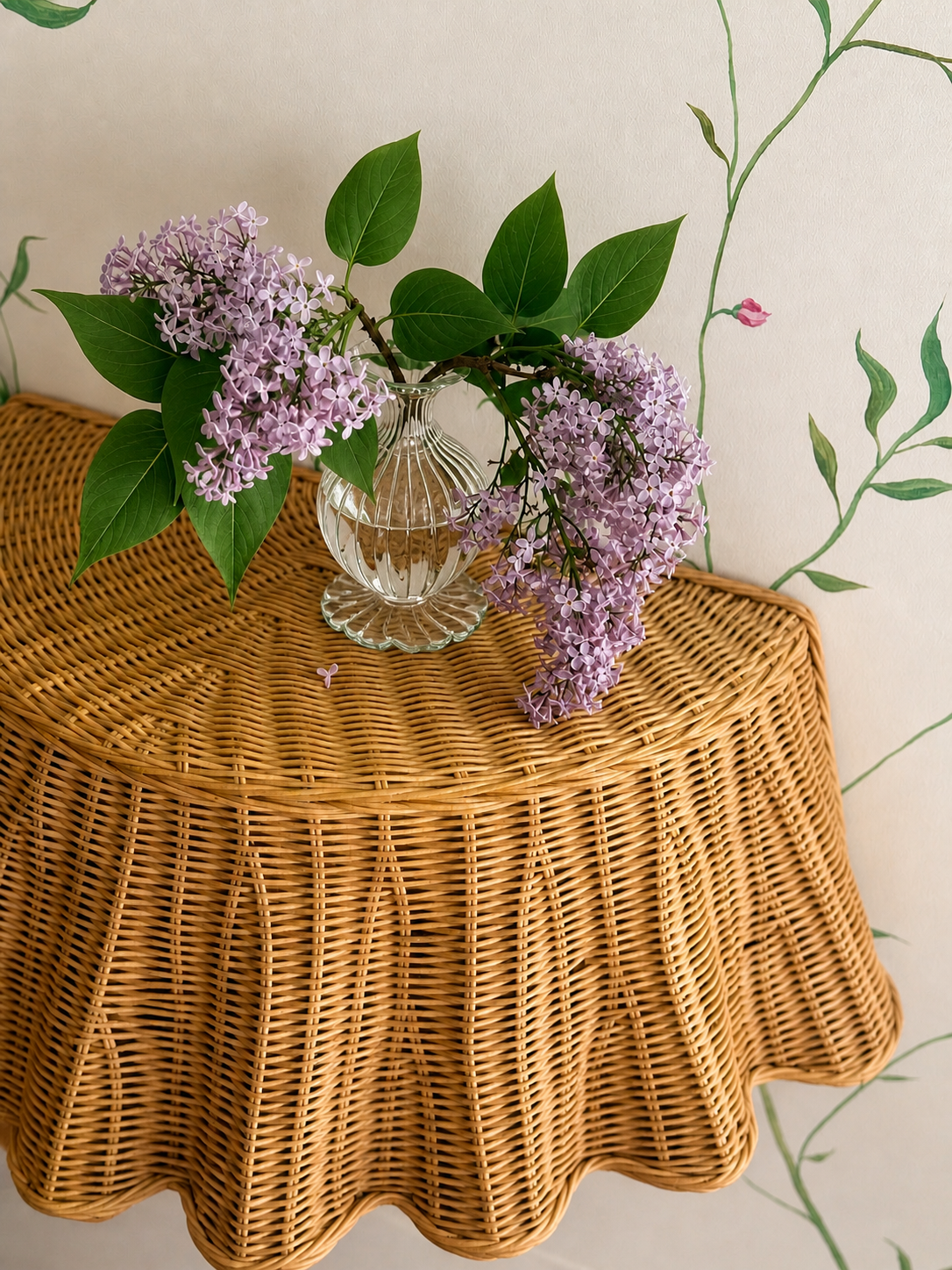 Floating rattan skirted table against hand painted botanical wall mural 