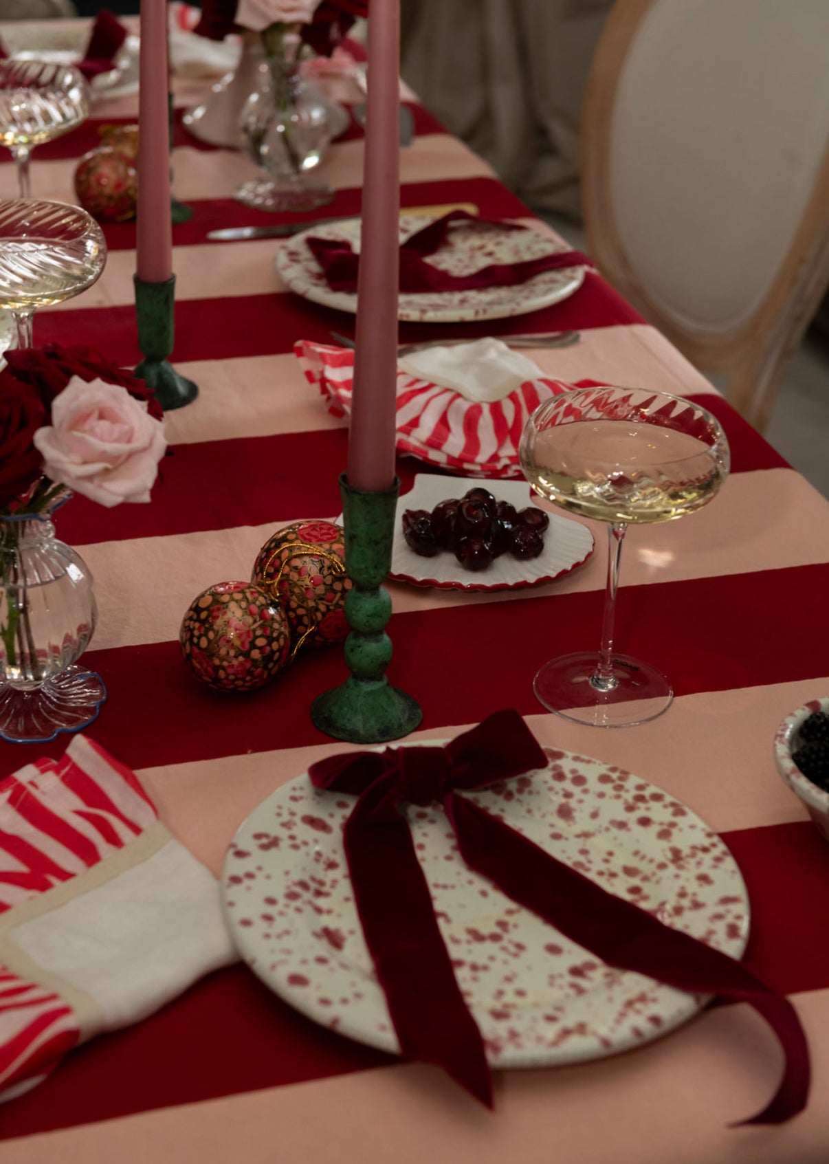 Decorative table setting with red and white striped tablecloth, candles, and a bow.
