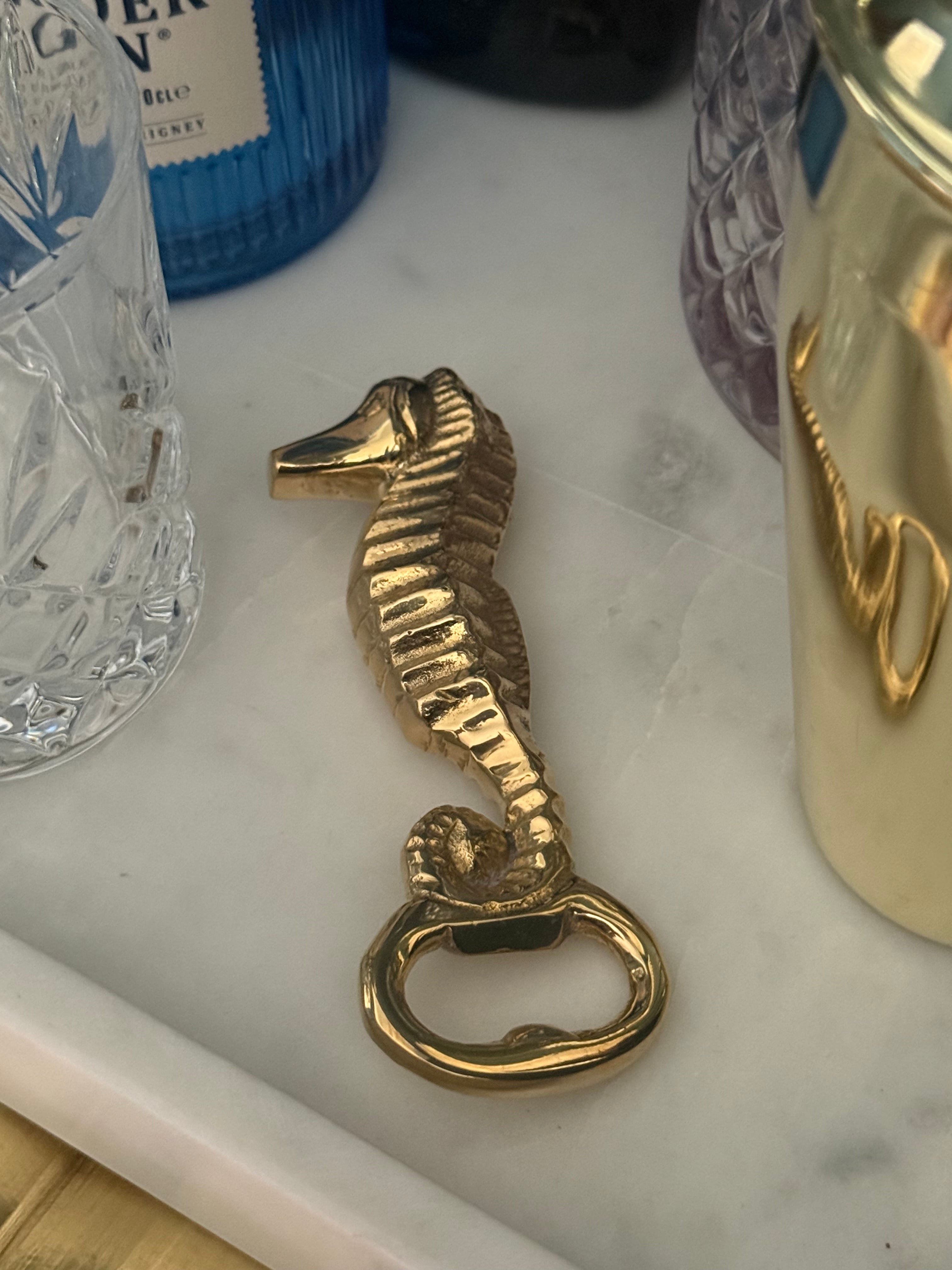 Gold seahorse bottle opener on a white surface with a blurred background