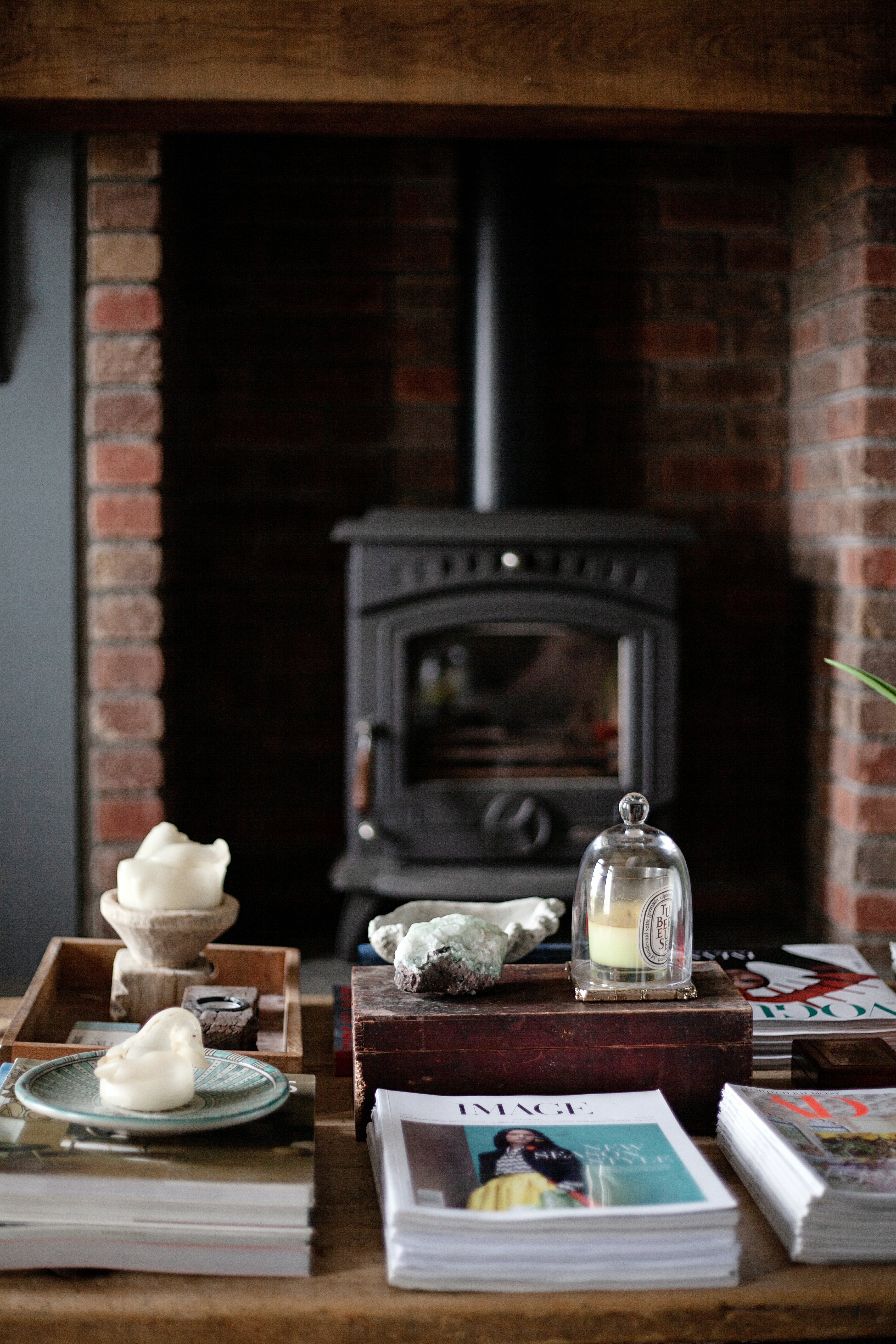 Wooden coffee table styling with decorative items in front of a brick fireplace with a stove.