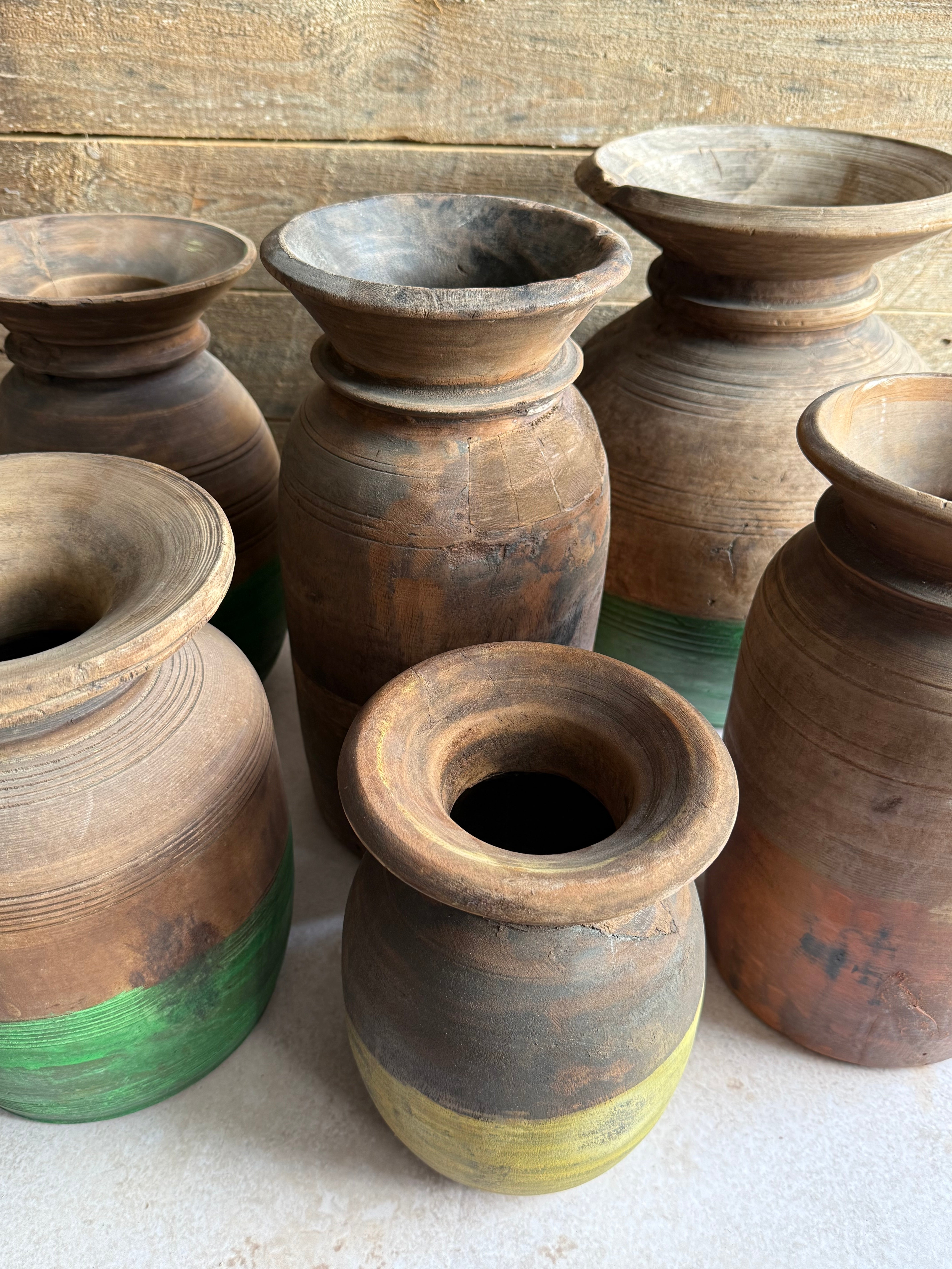 Stack of old wooden pots with green accents on a wooden surface.