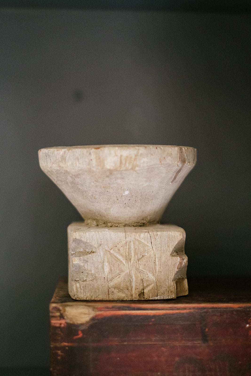 Detail shot of carved wood seeder against dark grey wall