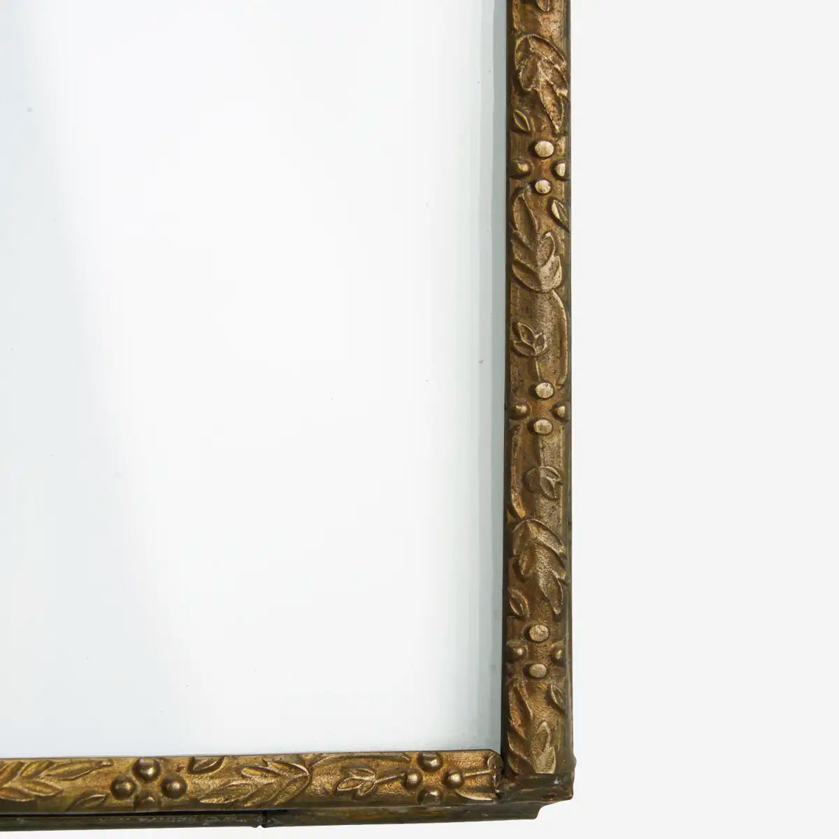 Detail of aged brass hanging photo frame with pressed flower imprint detail on white background