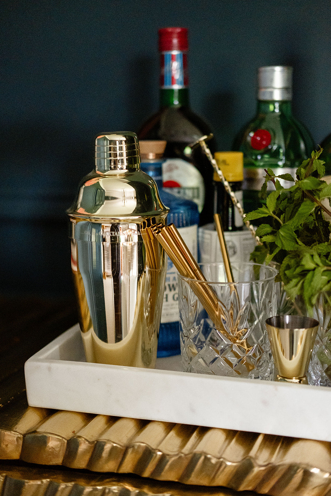 Cocktail shaker with bar tools on a tray against a dark background